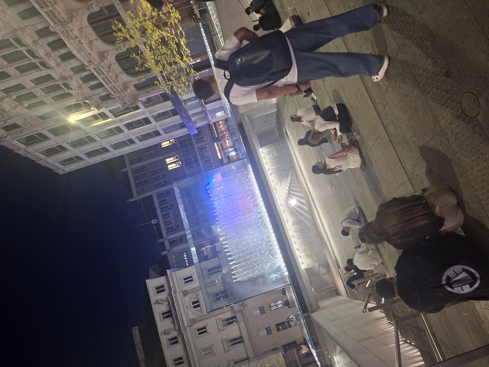 Evening crowd gathers at illuminated Milan water feature