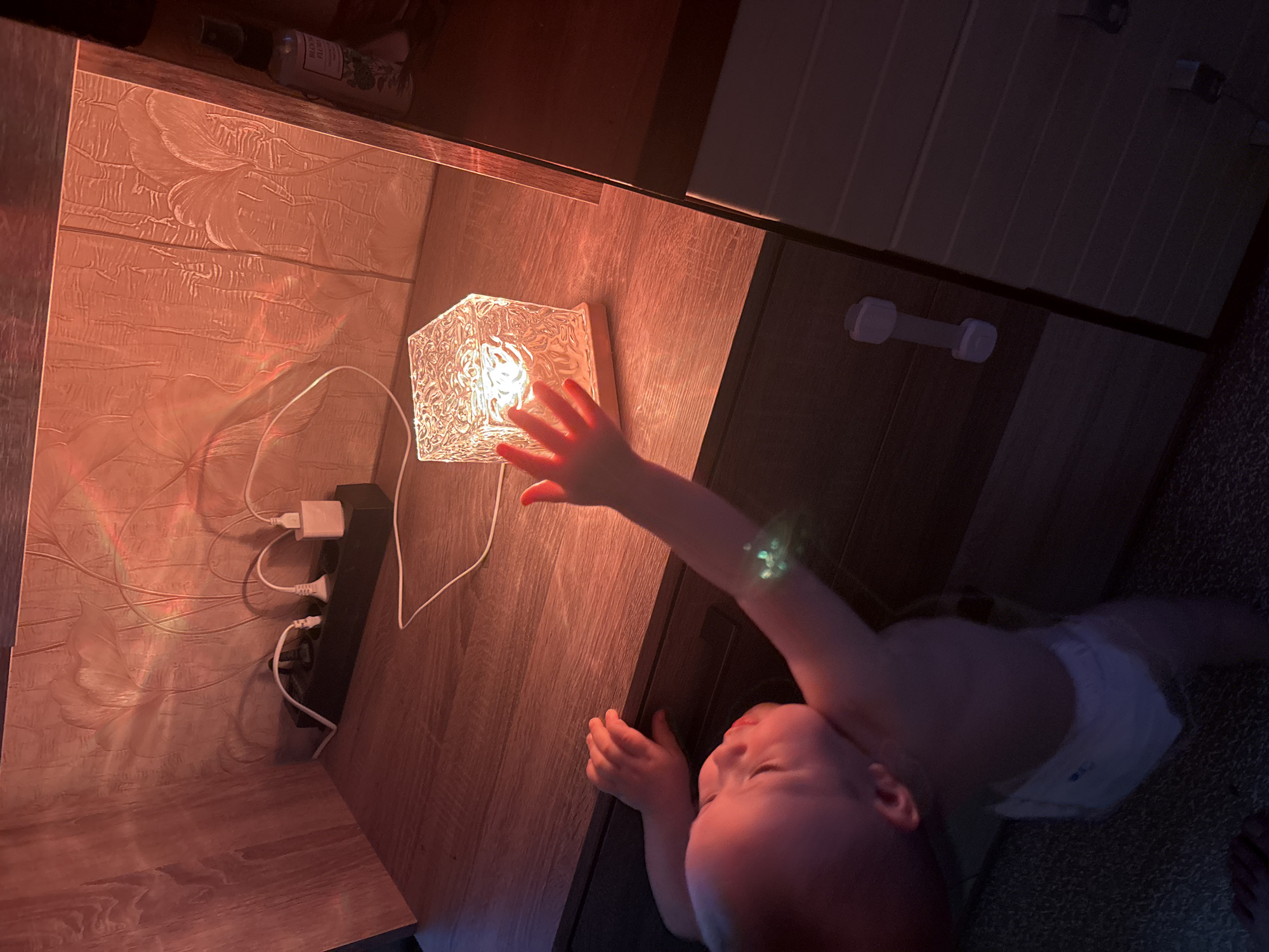 Baby plays with a glowing cube lamp at home