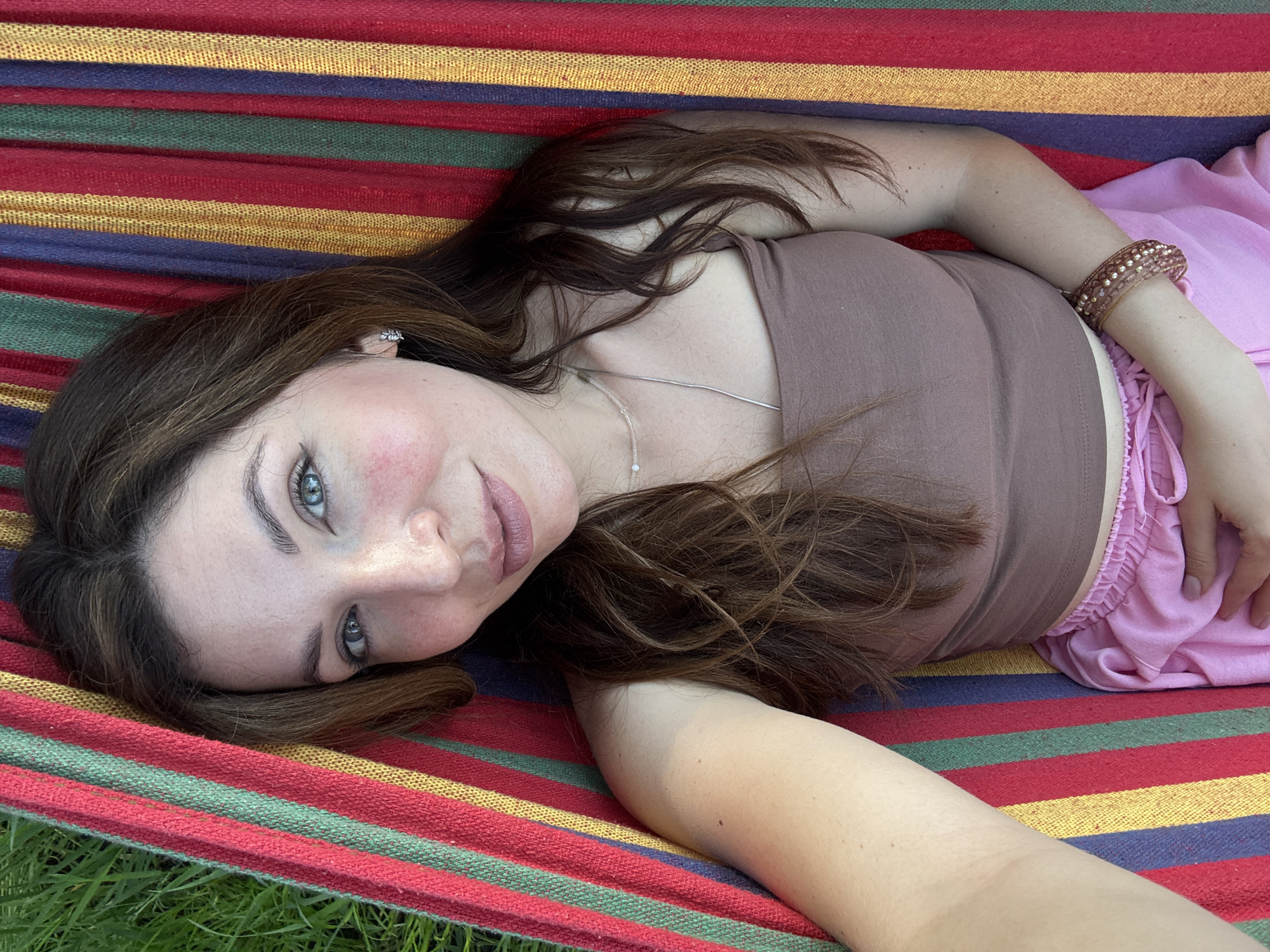 Woman relaxes in hammock under clear skies and trees