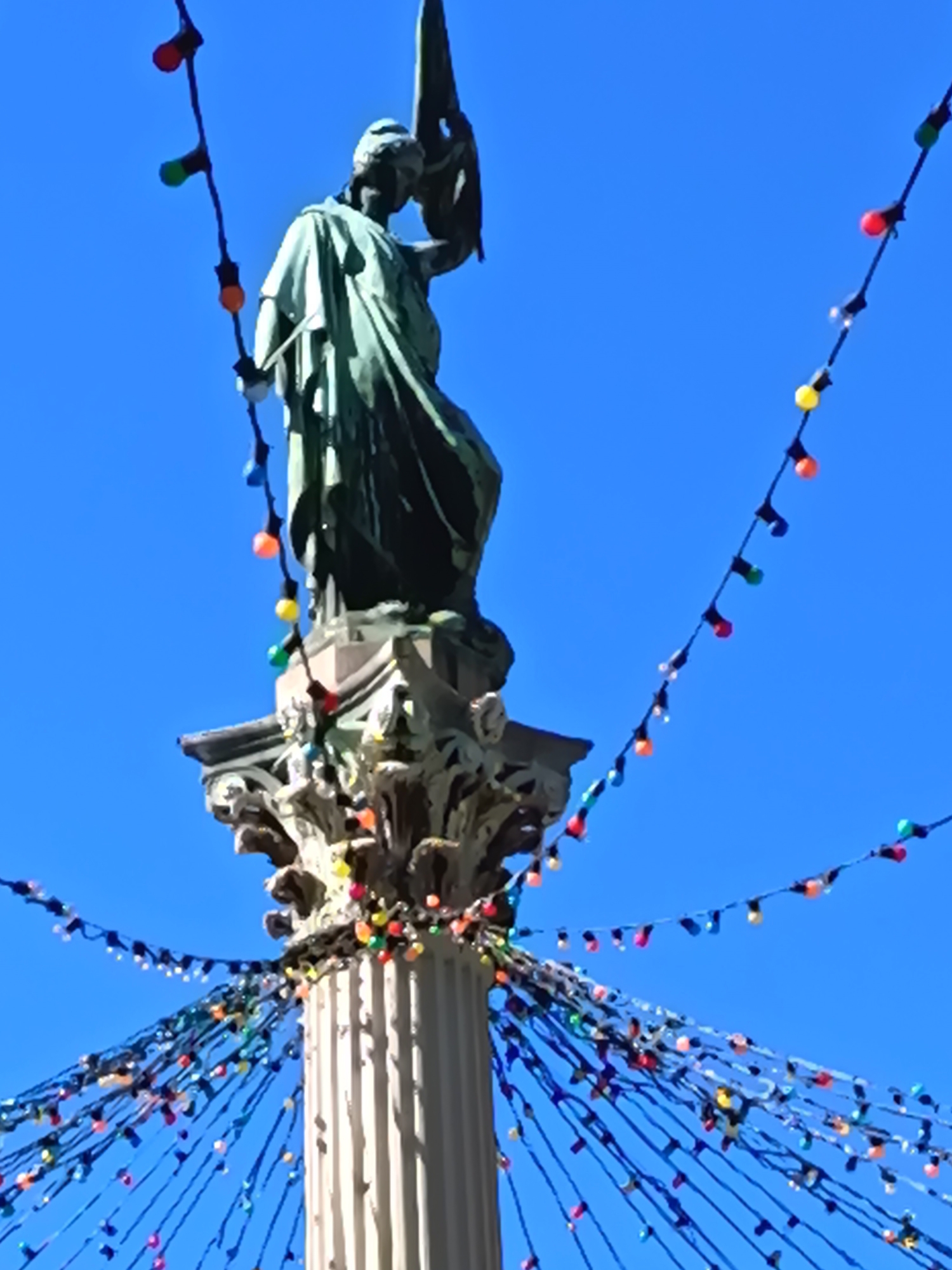 Statue decorated with colorful lights observed on ornate column