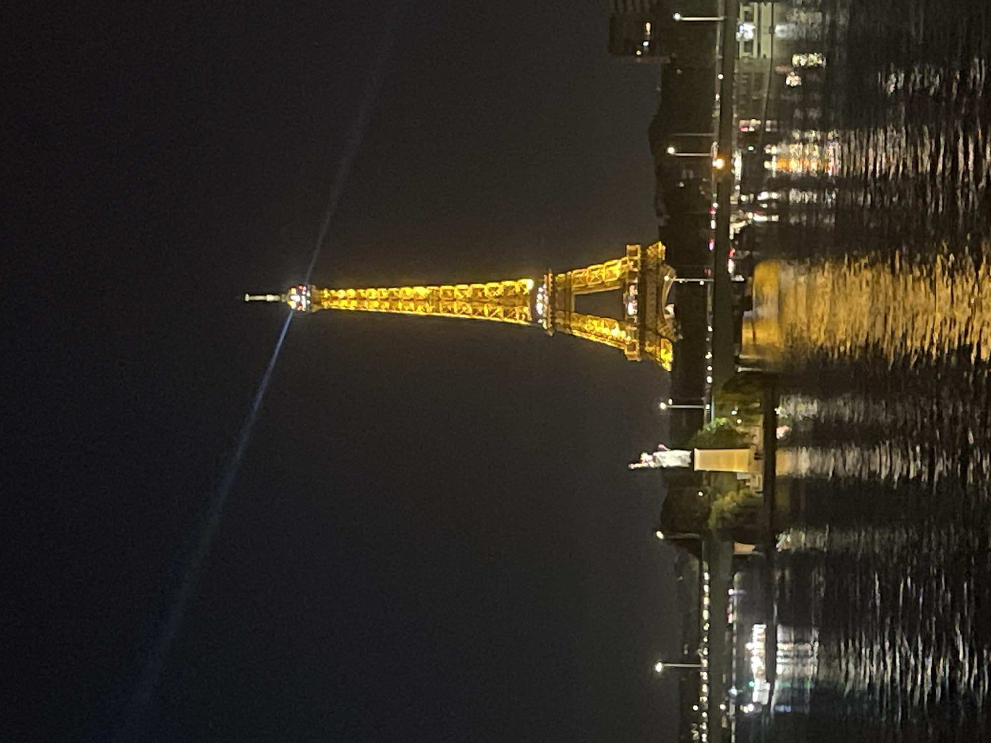Eiffel Tower glowing gold over the Seine at night