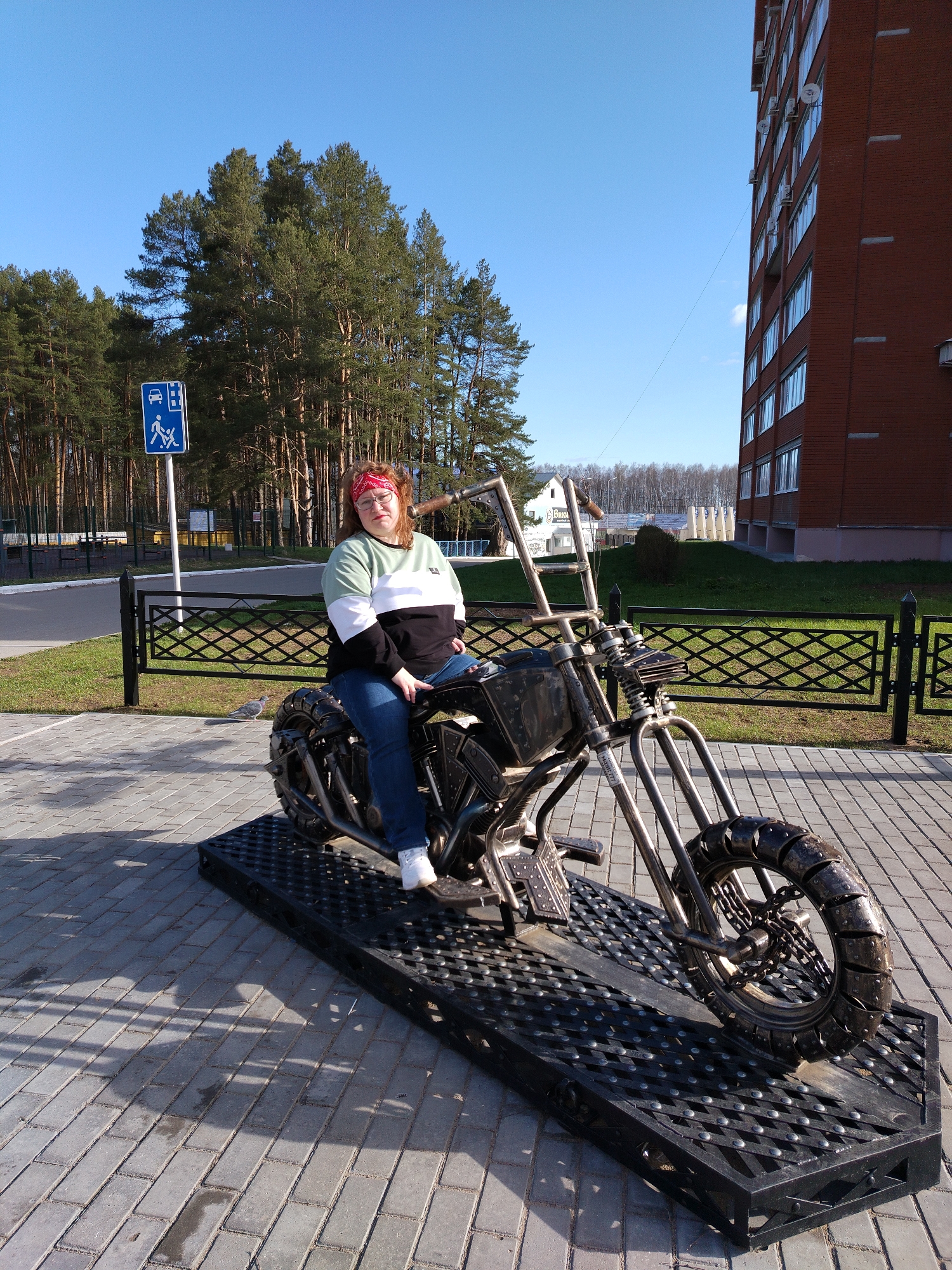 Woman poses on motorcycle sculpture in Chaikovsky, Russia