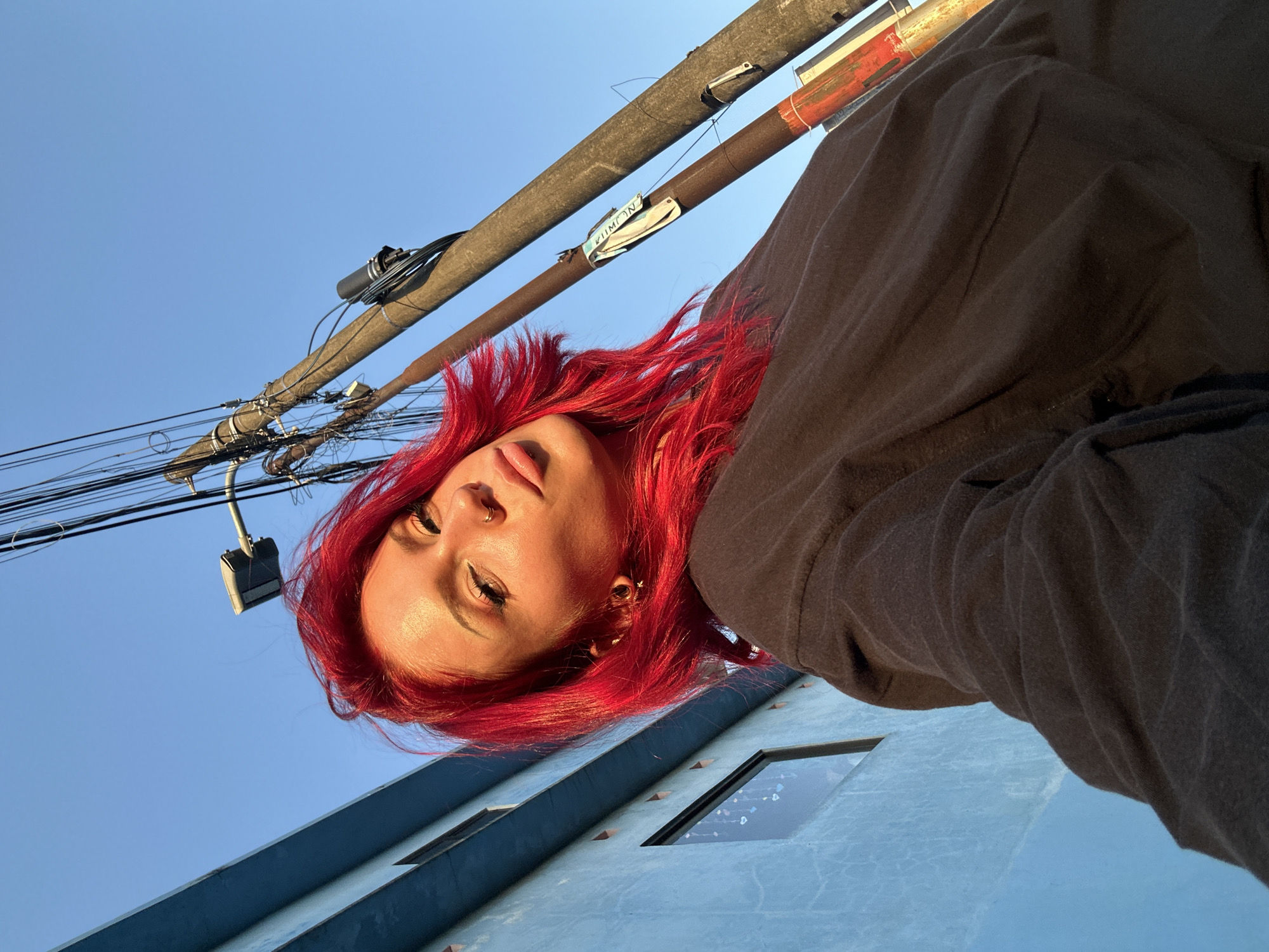 Red-haired selfie series outside a blue building in North Kuta