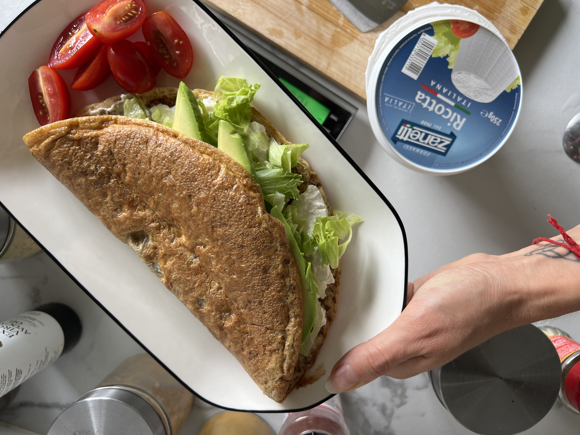 Person prepares breakfast plates with eggs, rice, crepes