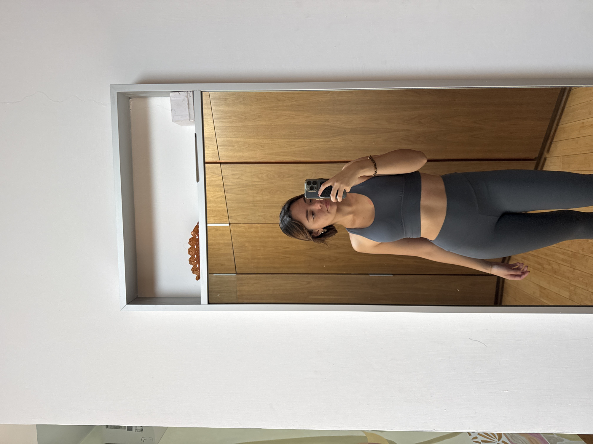 Woman takes mirror selfie in gray athletic wear