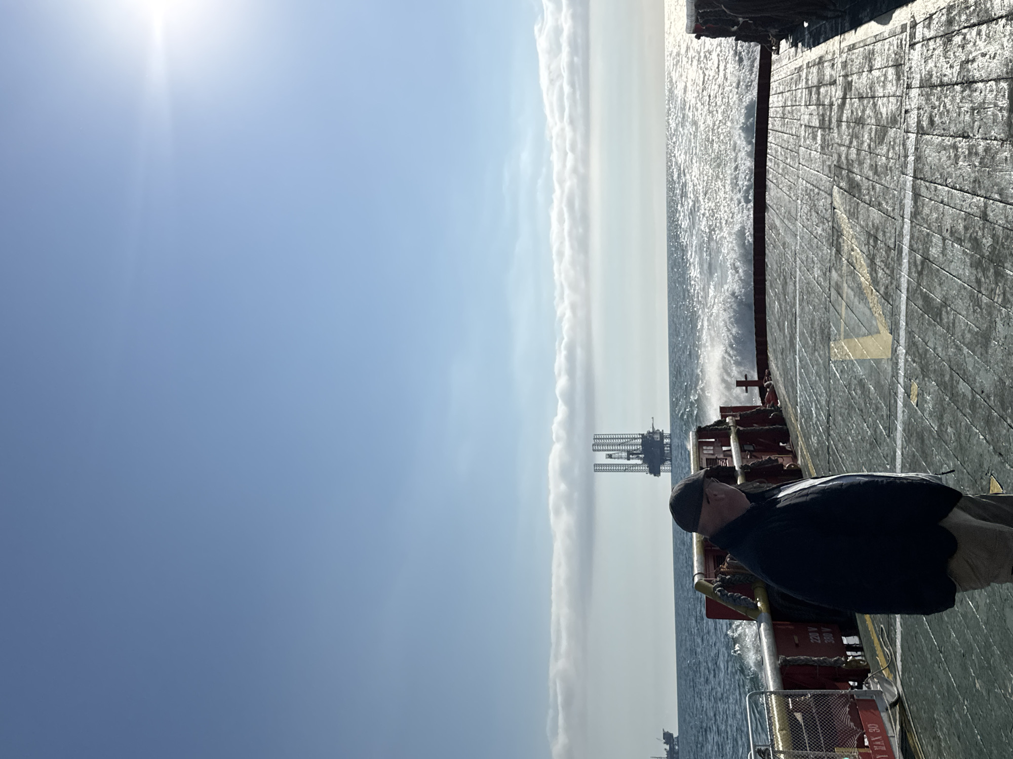 Man observes oil rig from ship deck in Italian waters