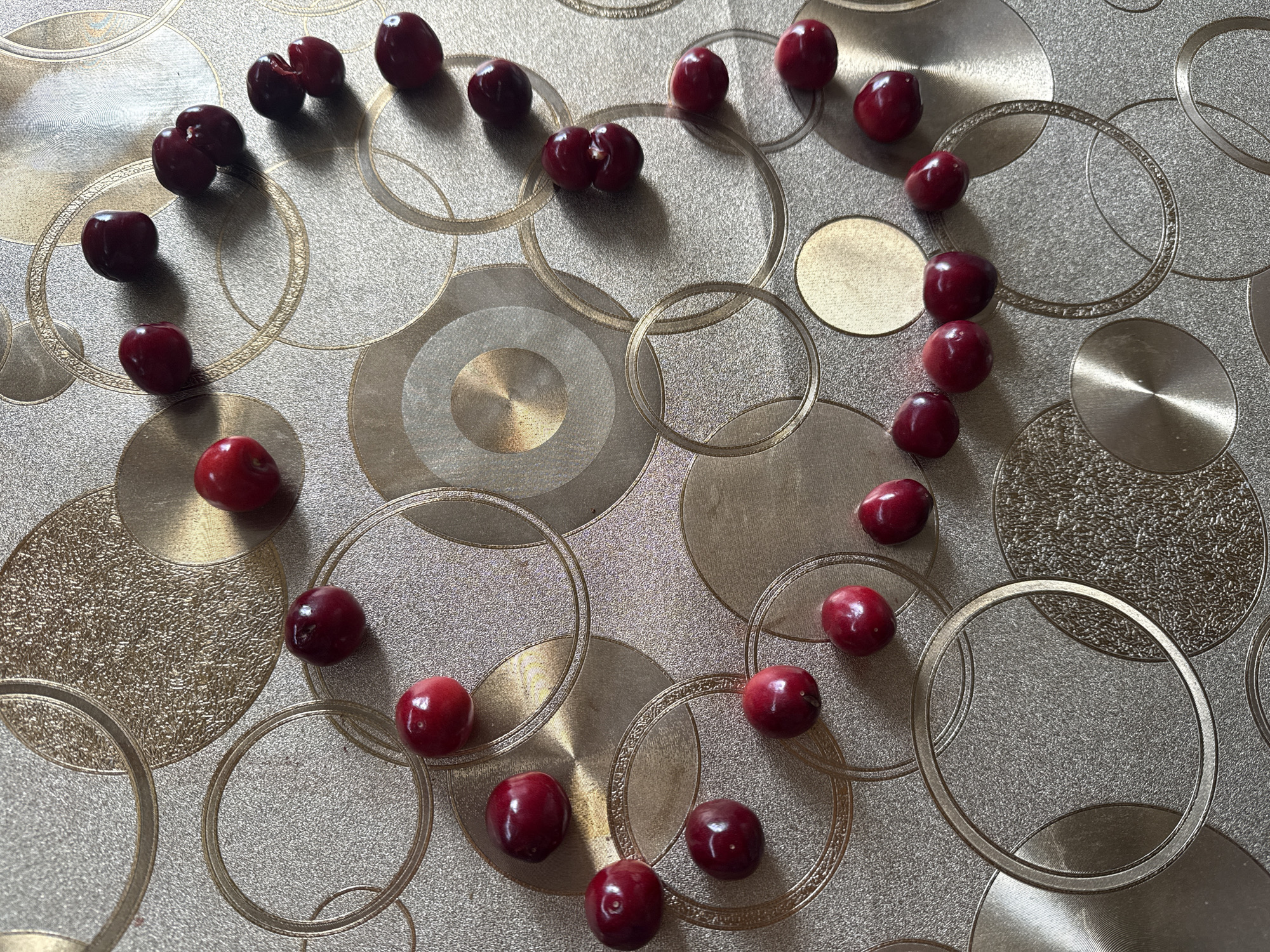 Red cherries scattered on decorative metallic surface