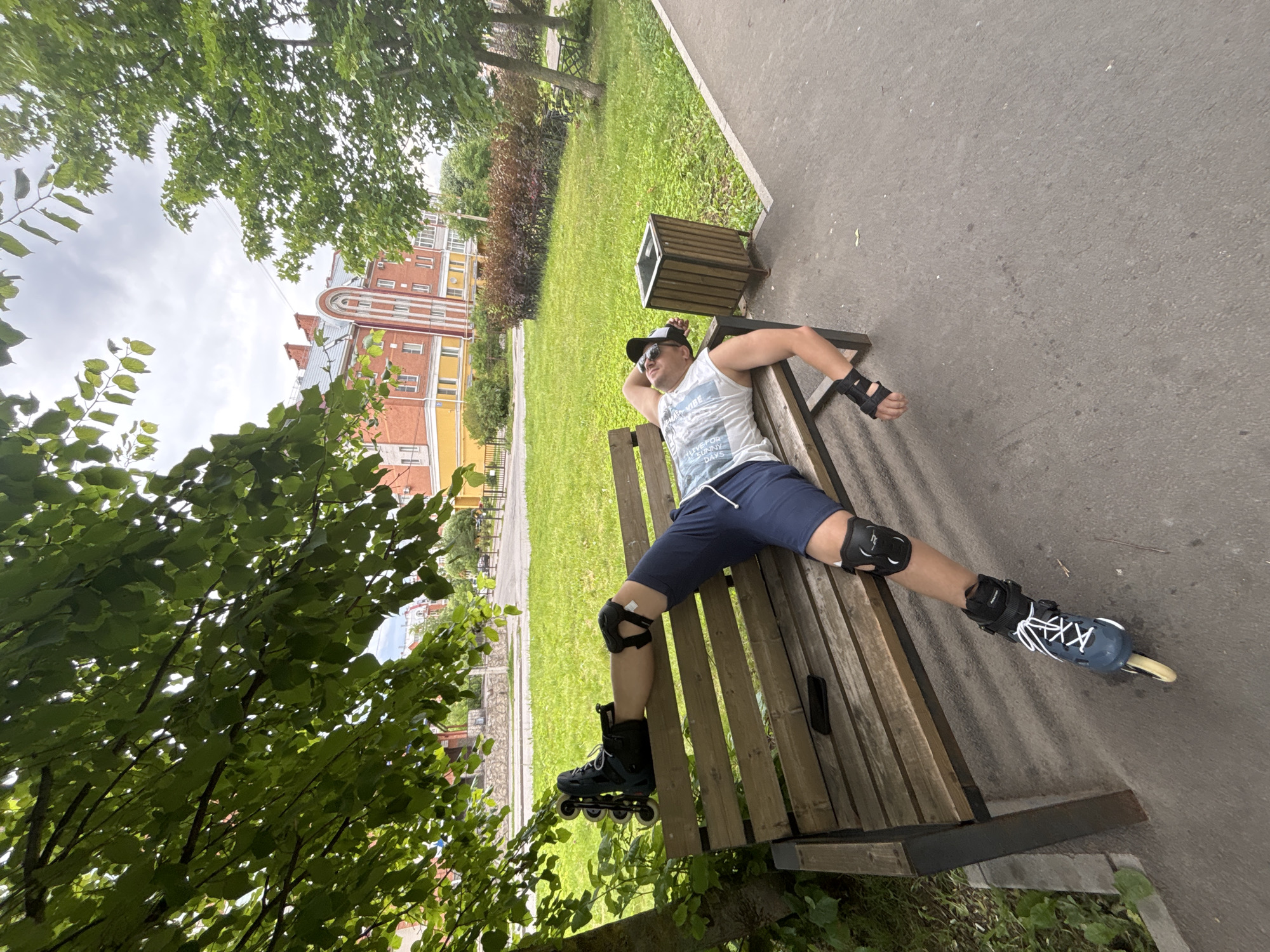 Rollerbladers resting on benches along a shaded urban park path