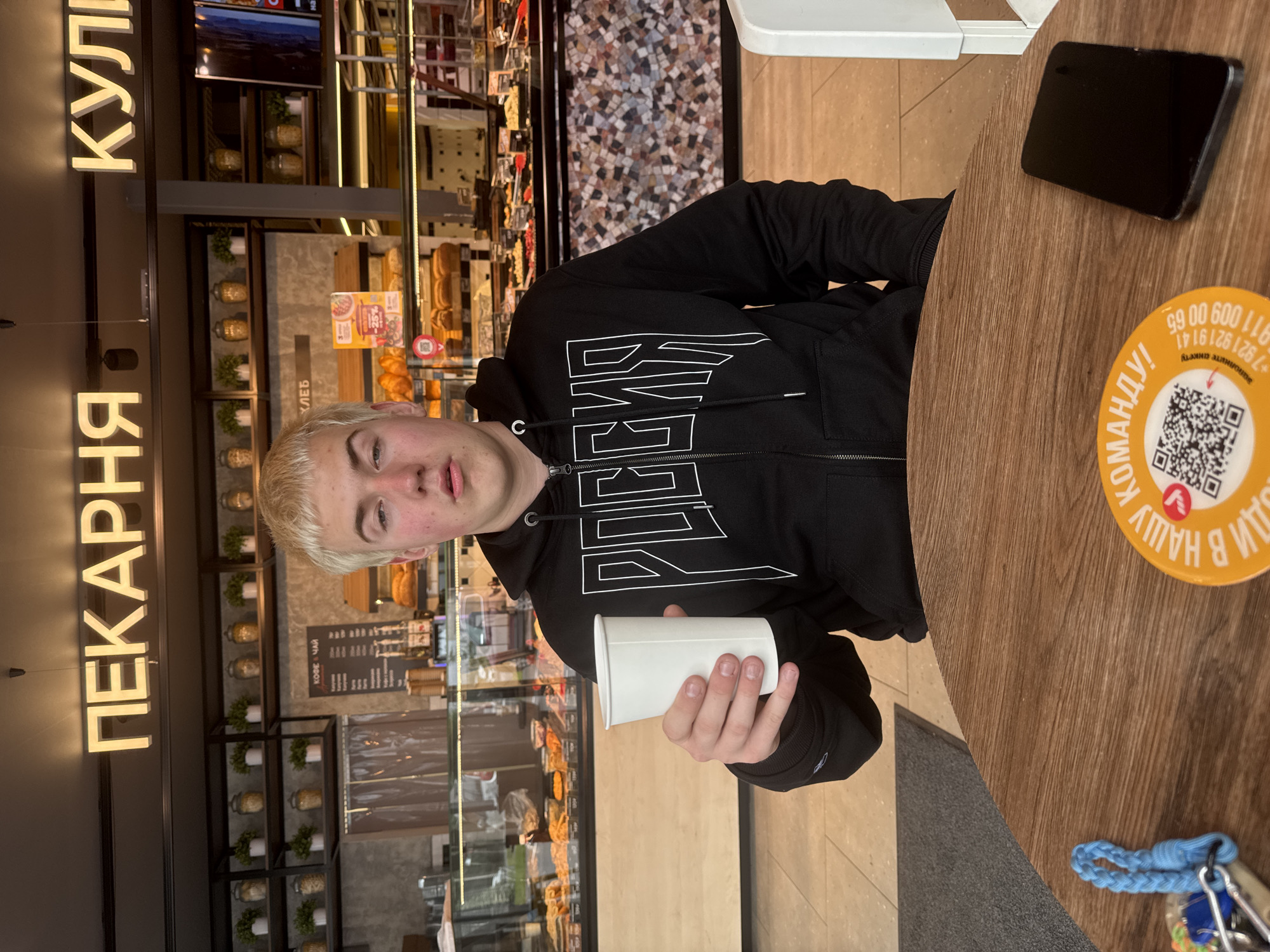 Young man in Russian hoodie observed at cafe table