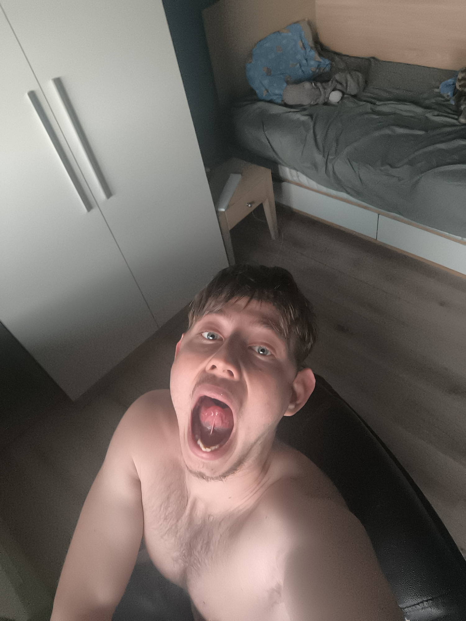 Man takes selfie showing tongue piercing in Sofia bedroom
