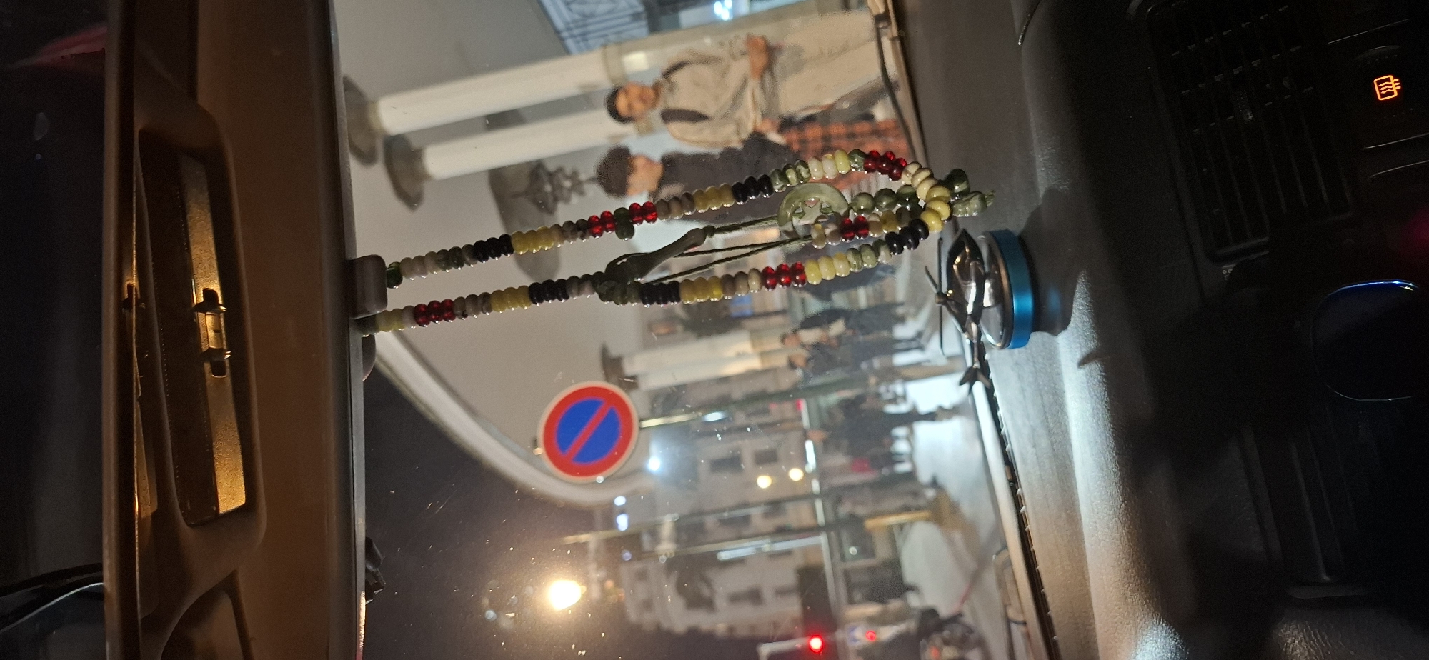 Pedestrians walk along Rabat sidewalk, captured in rearview mirror