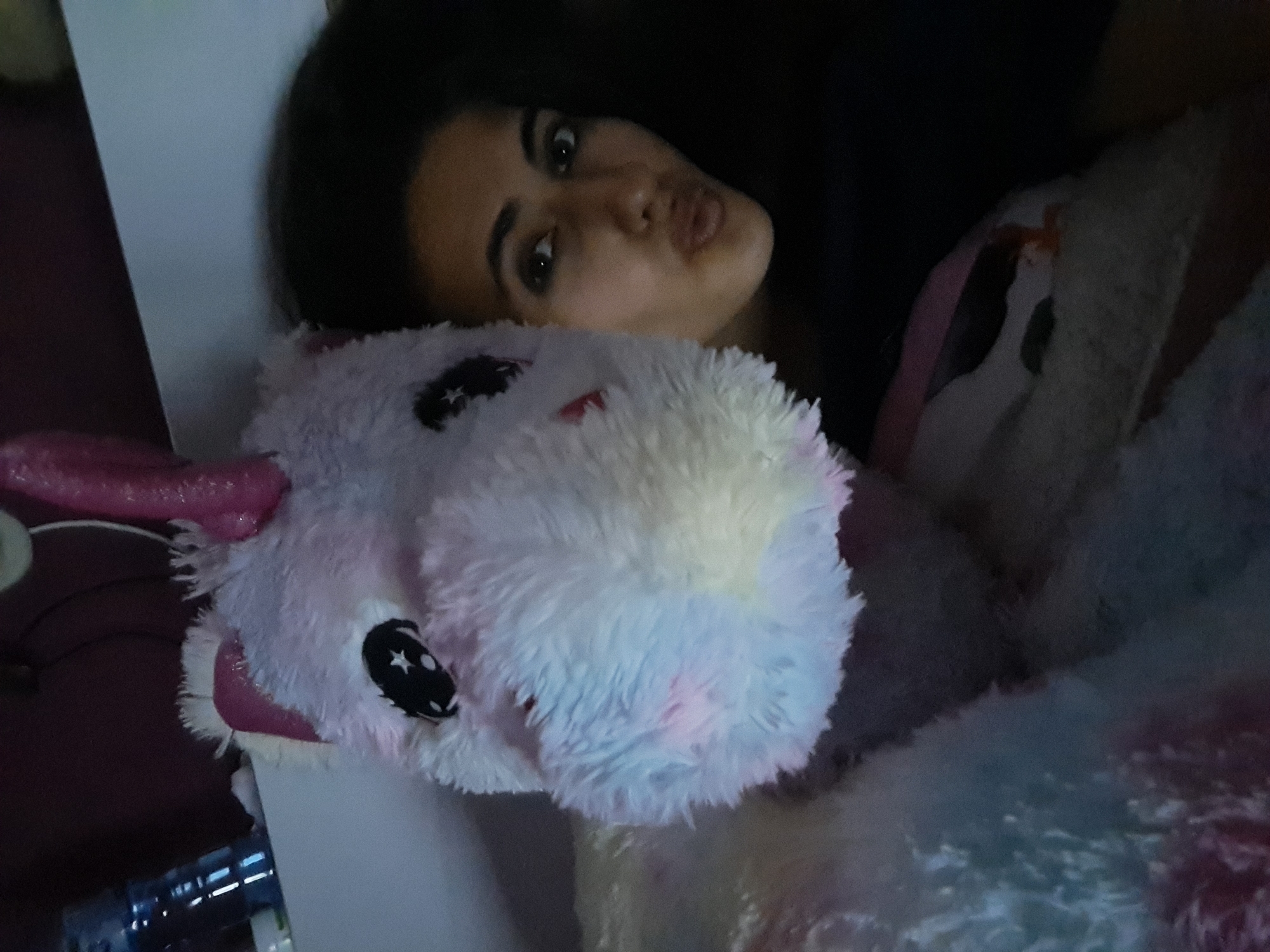 Person shares quiet evening with unicorn plush, candles