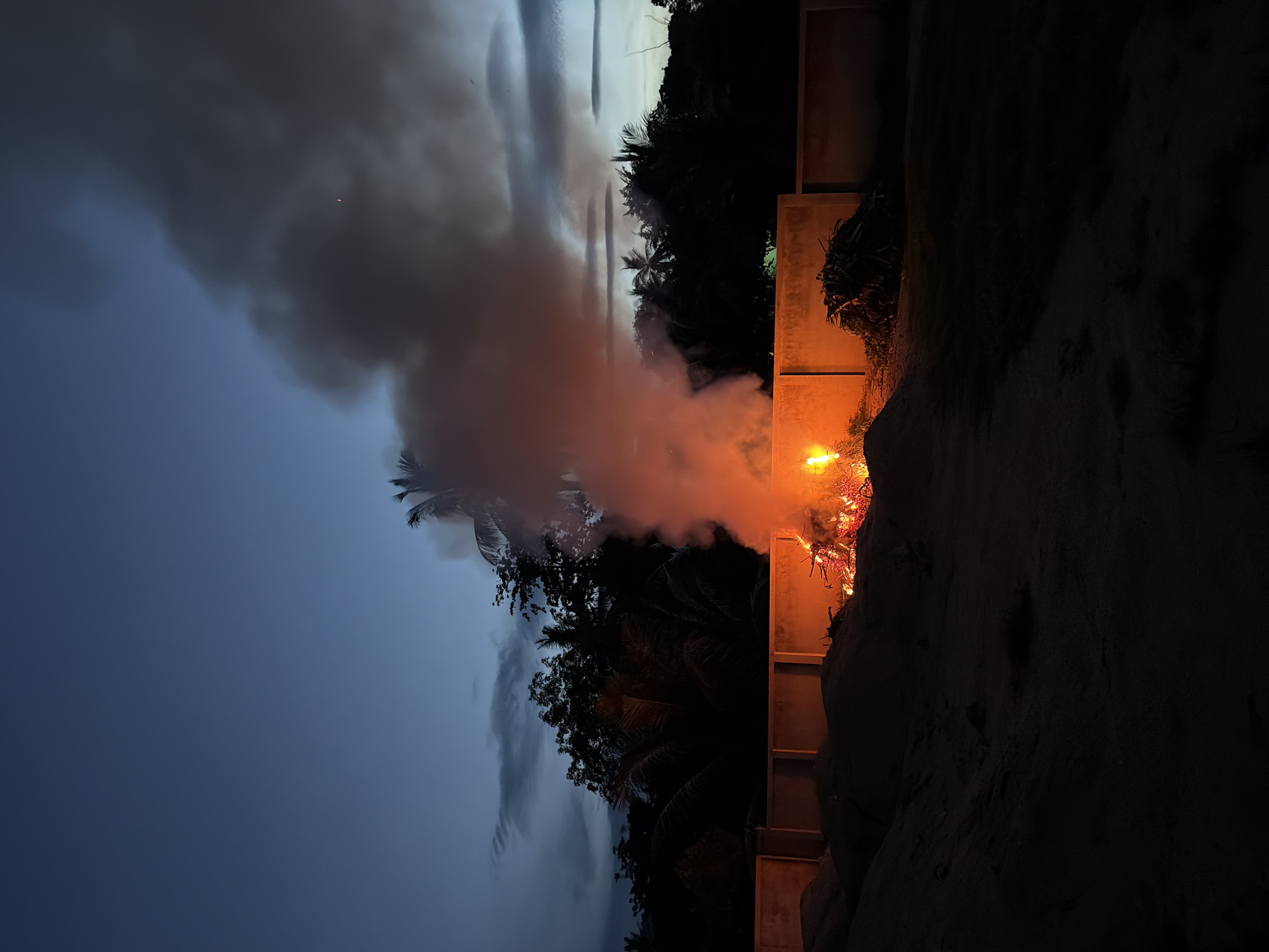 Bonfire burns at dusk under a crescent moon in Baan Mae Nam