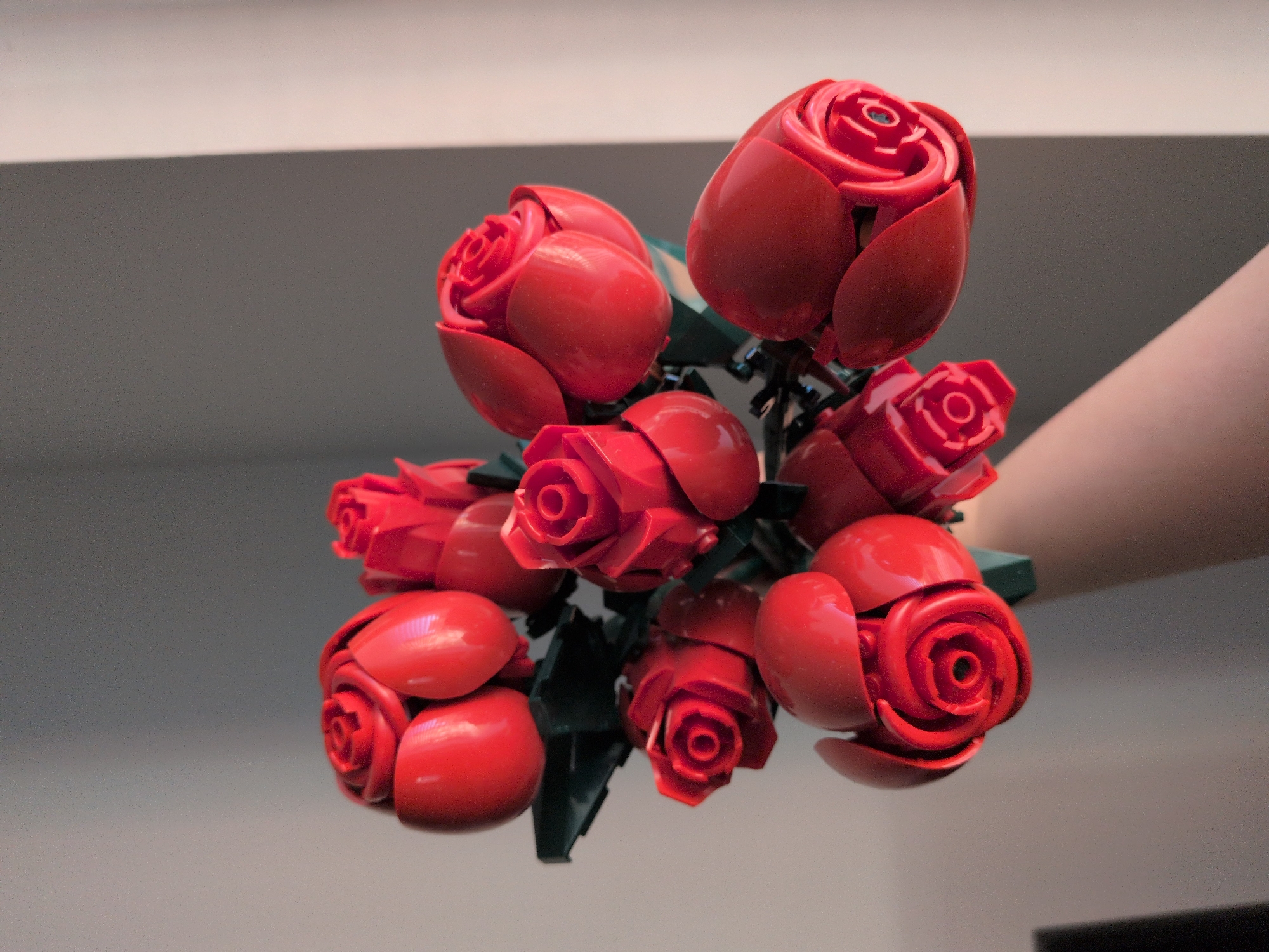 Person displays handmade LEGO rose bouquet in unknown location