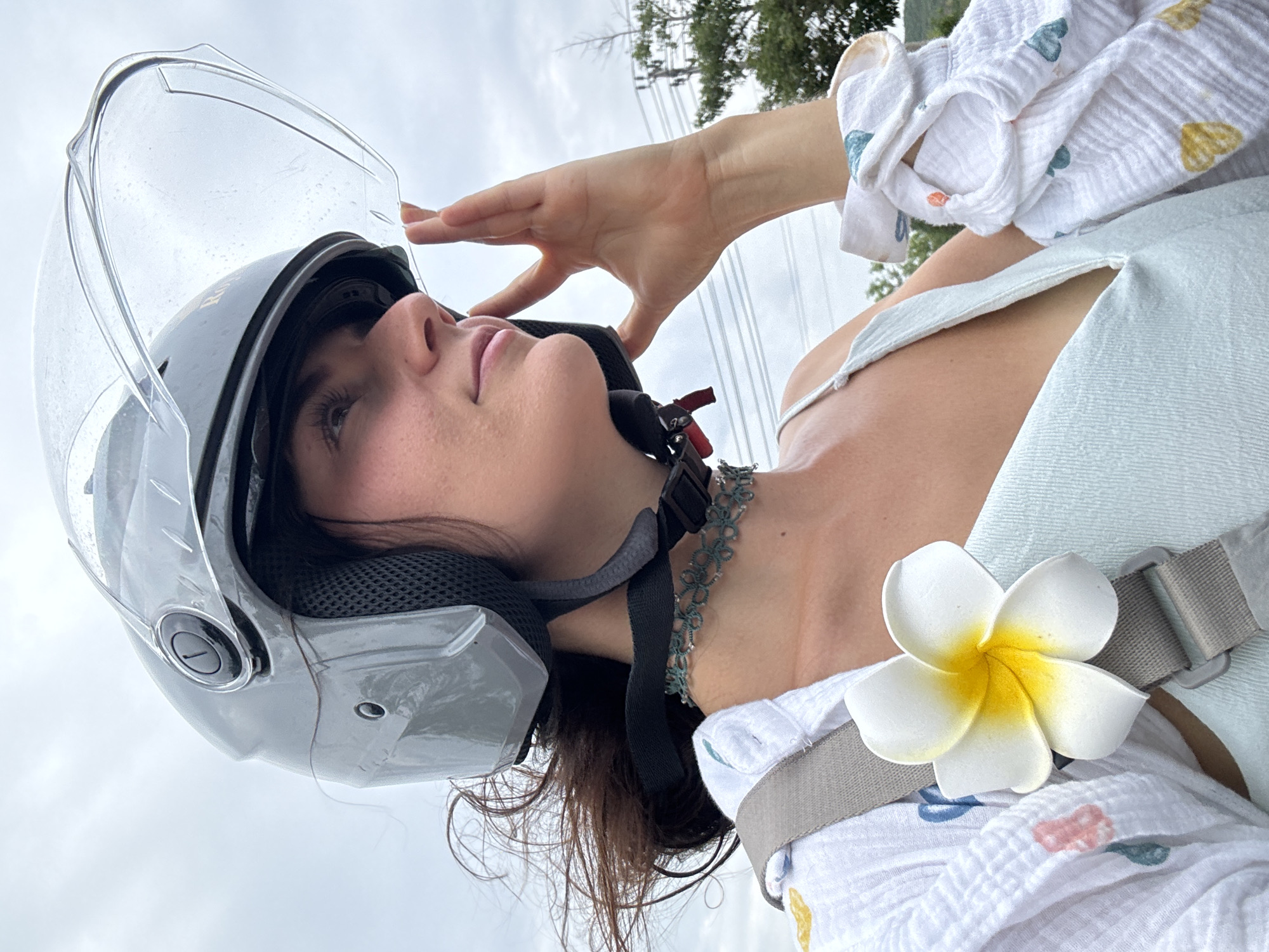 Woman adjusts motorcycle helmet in rainy Mui Ne morning