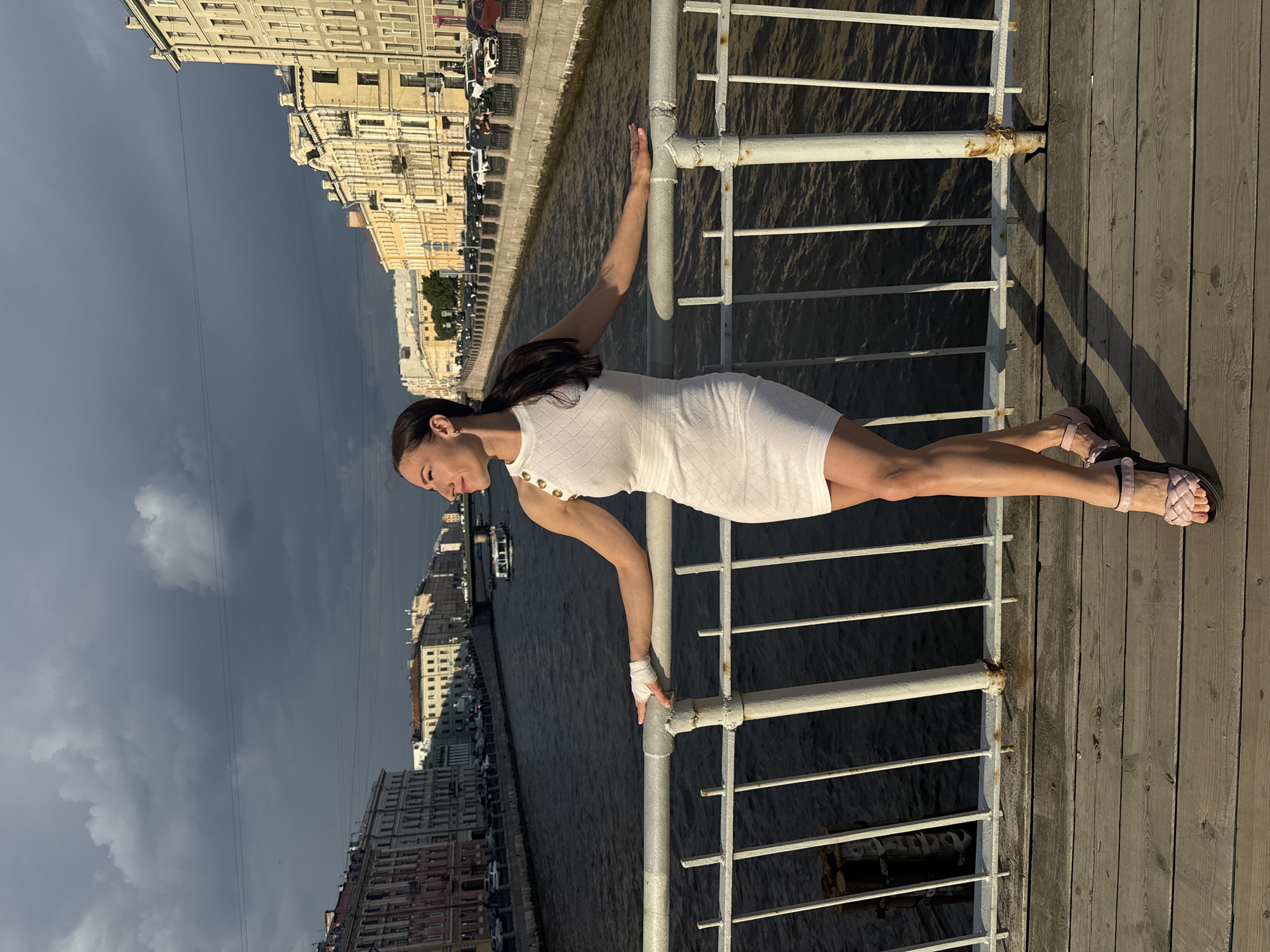 Woman poses dynamically on Saint Petersburg pier overlooking waterway