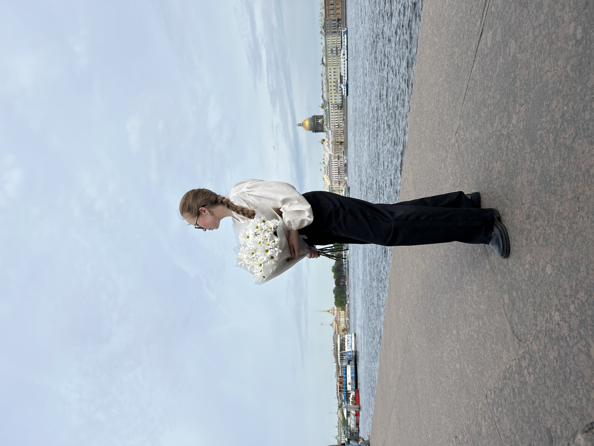Woman with white flowers walks Saint Petersburg embankment