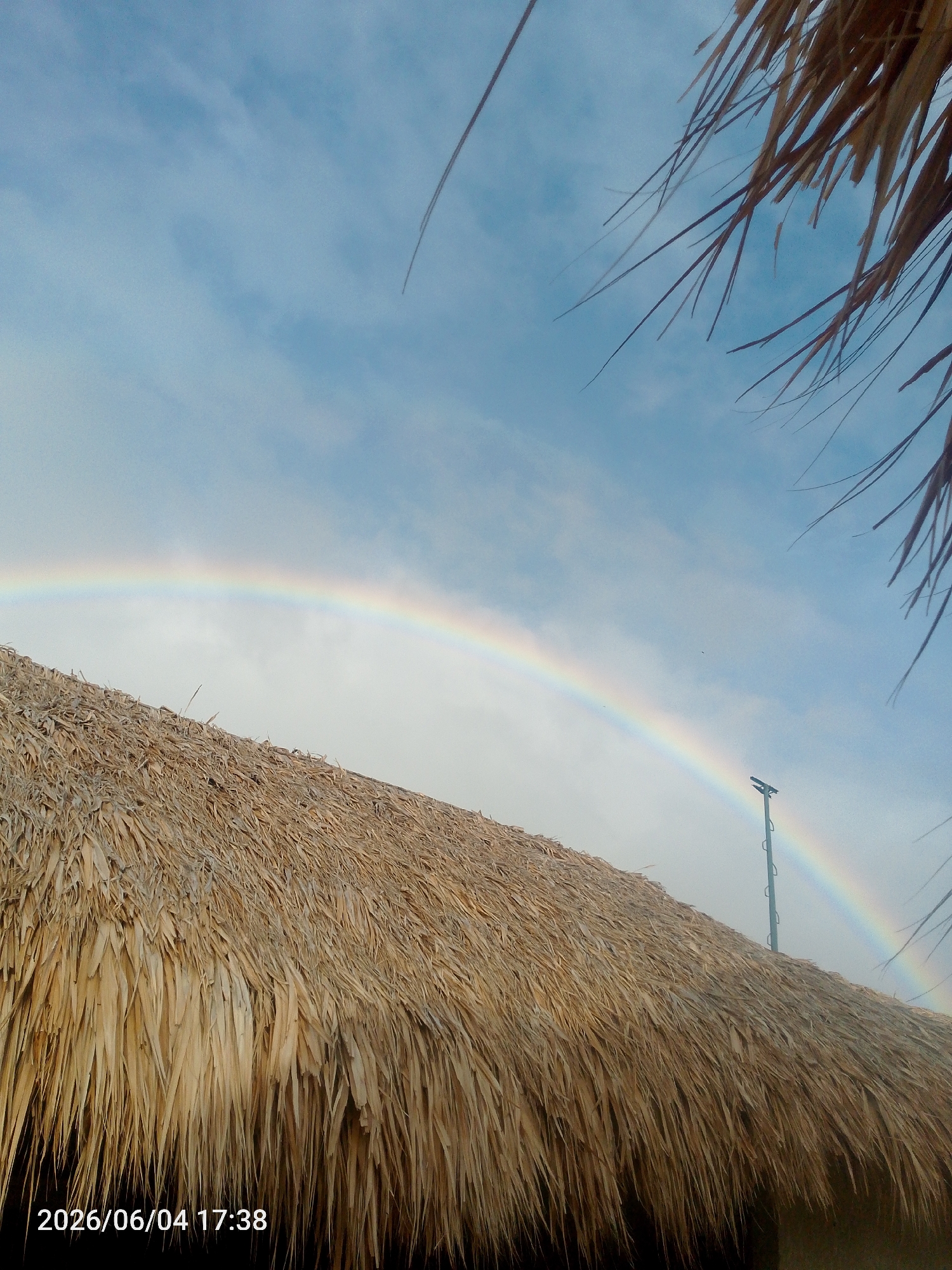Rainbow observed over tropical resort during evening hours