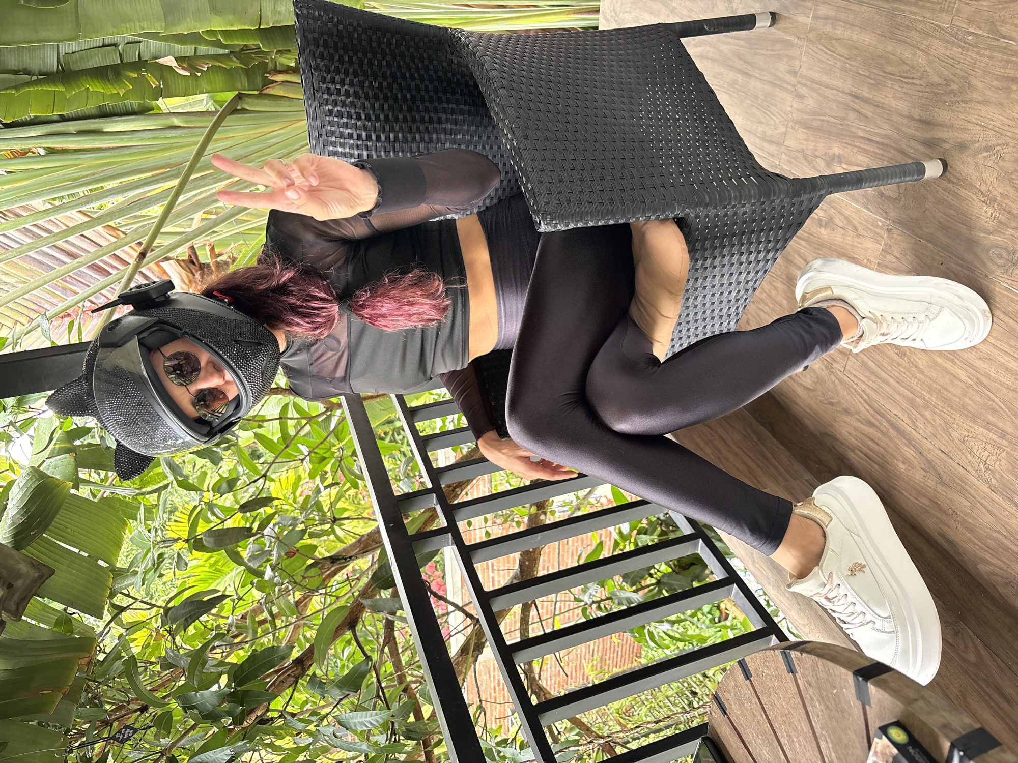 Cat-ear helmet and all-black fit in a tropical outdoor setting