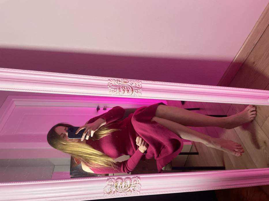 Woman takes mirror selfies in pink-lit room in Batumi