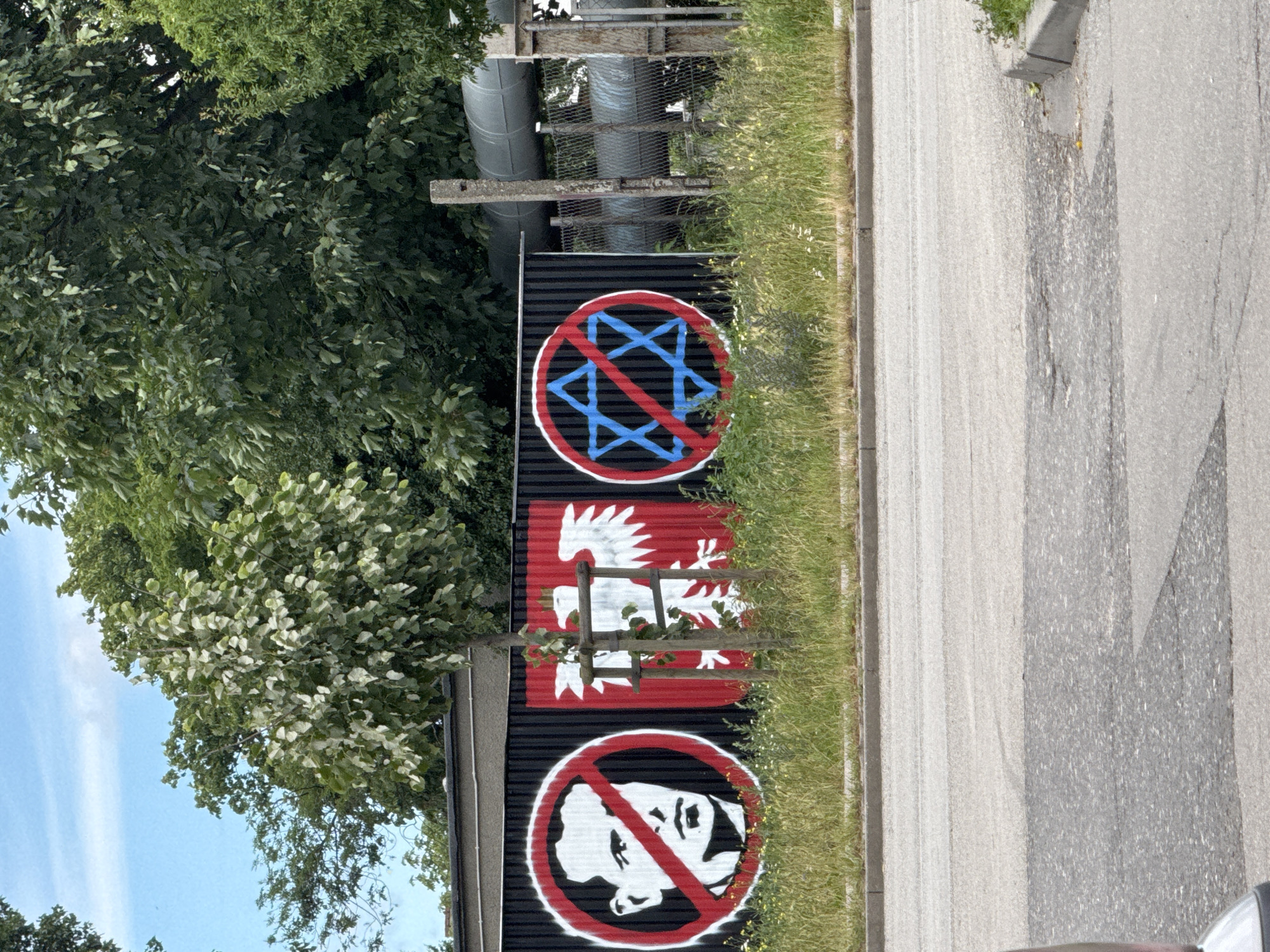 Street art tags and stencils on a corrugated fence in Gdańsk