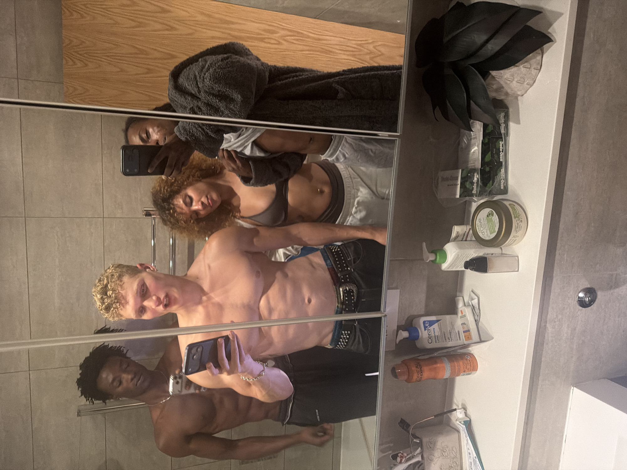 Young adults take group mirror selfies in London bathroom