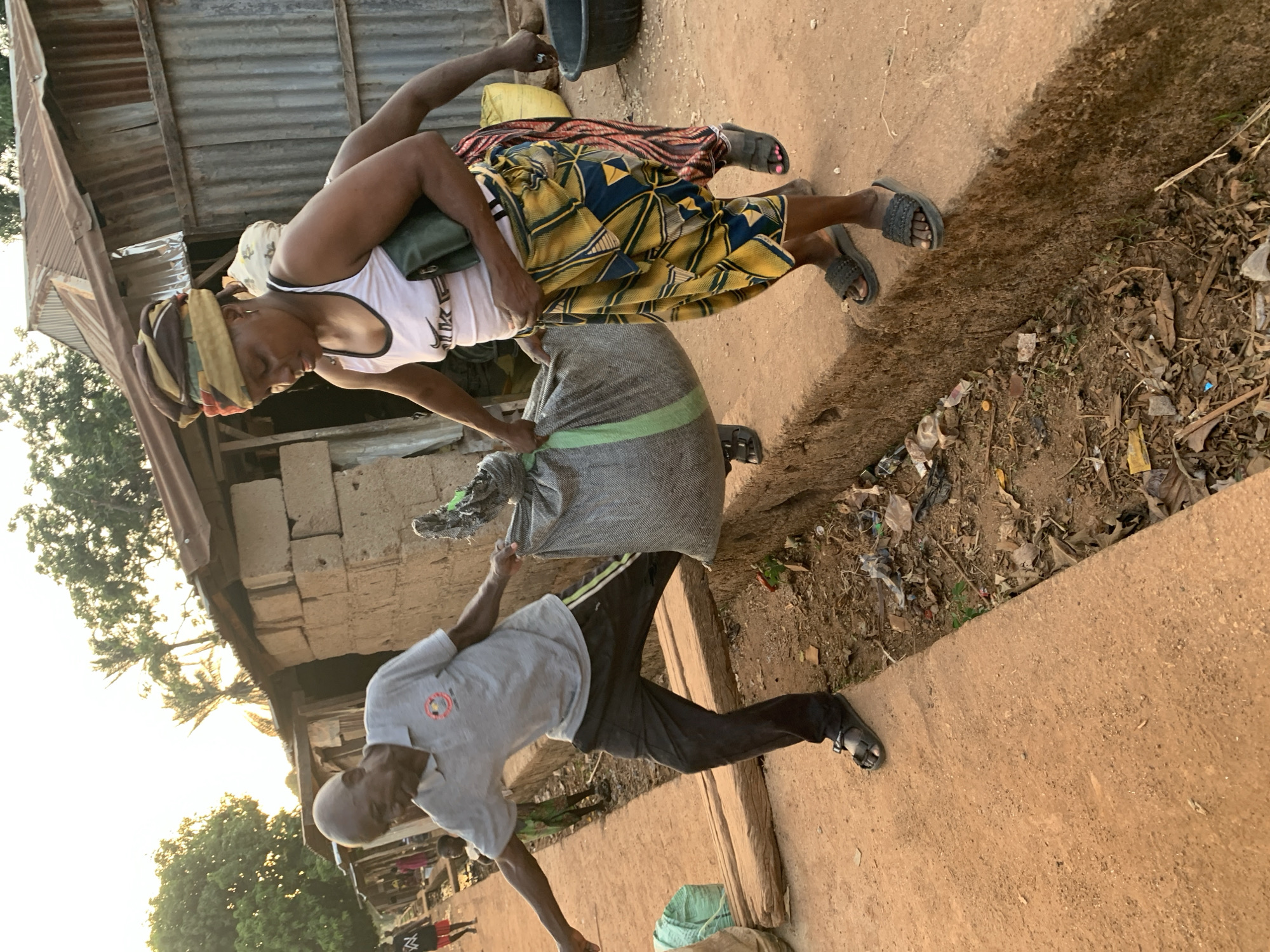 Woman processes grains outdoors in Agban, Nigeria