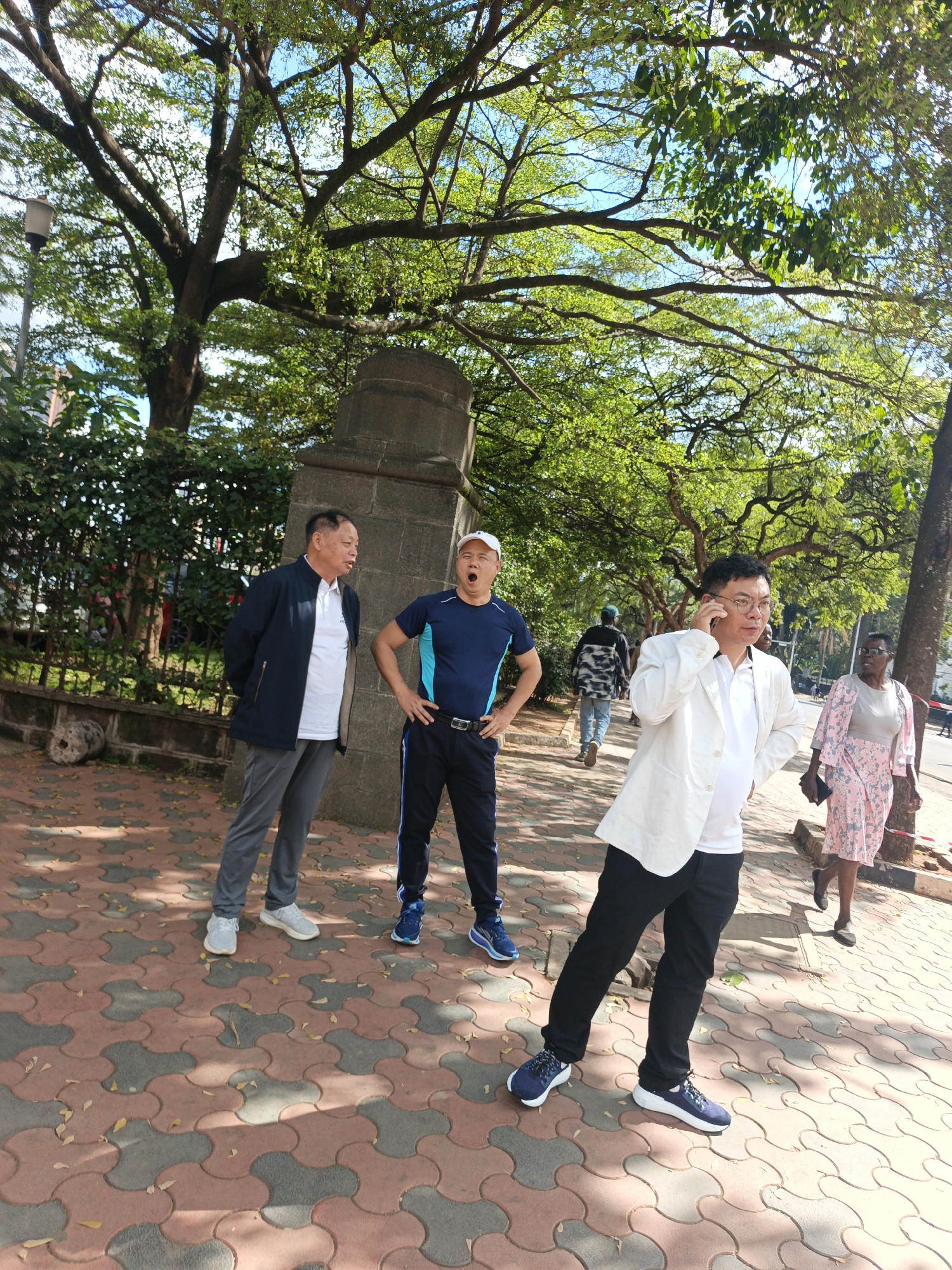 Four people gather on Nairobi sidewalk near concrete pillar