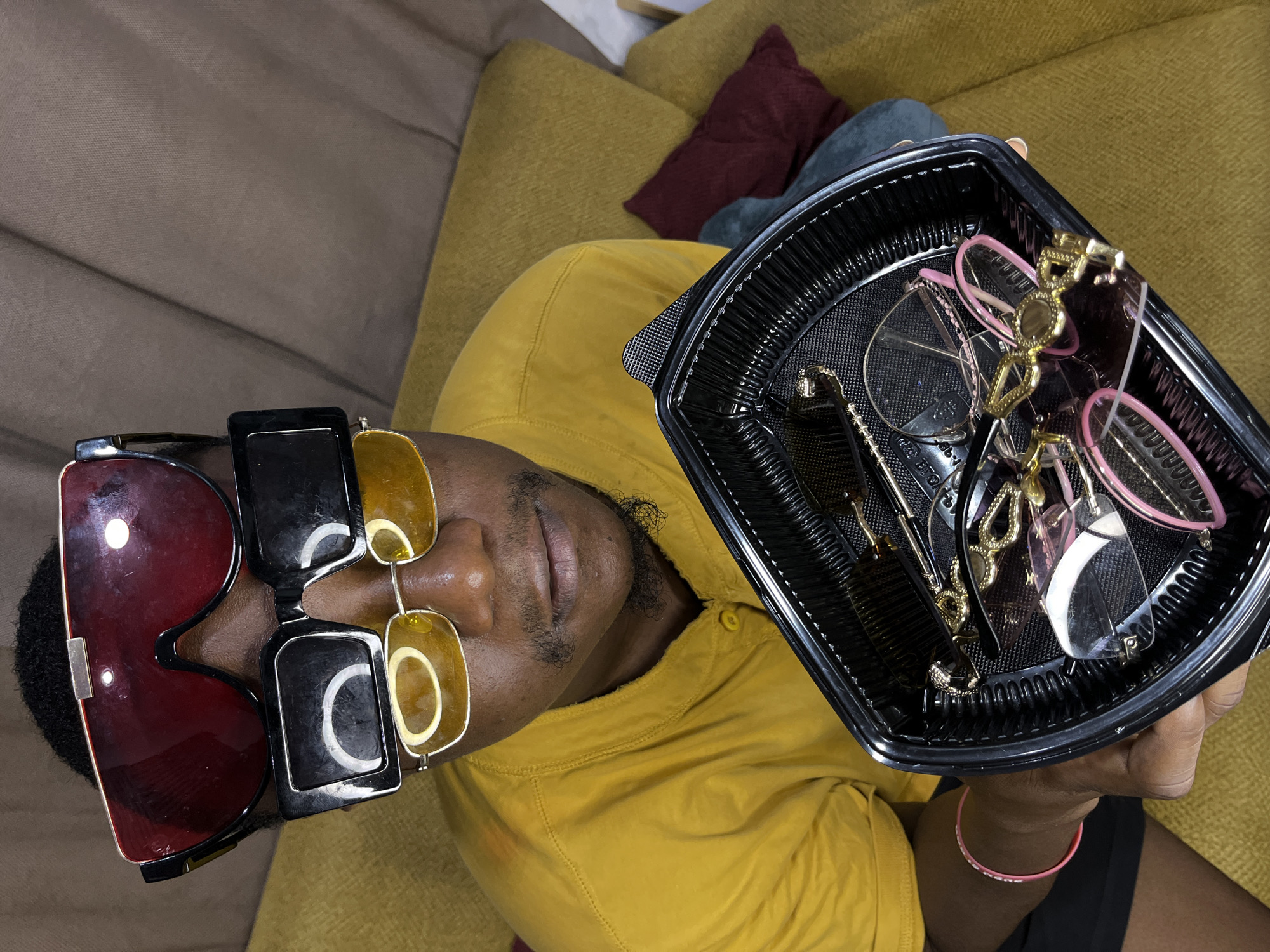 Sunglasses vendor displays eyewear collection on couch in Accra