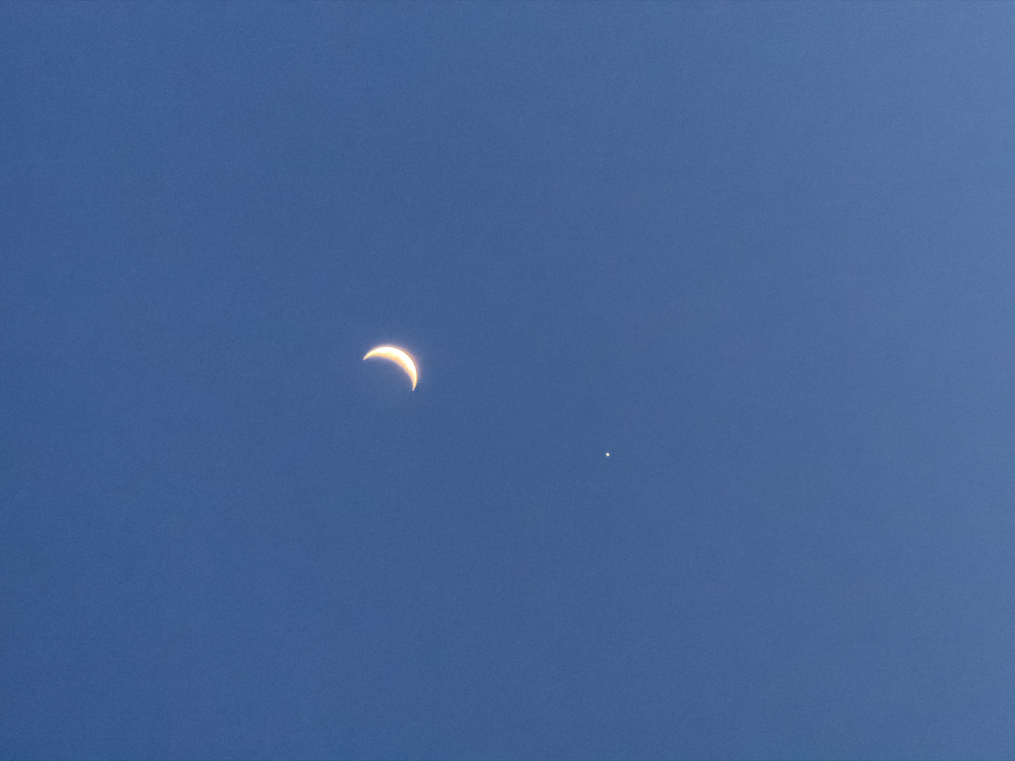 Crescent moon and bright celestial object visible in Krasnoyarsk daytime