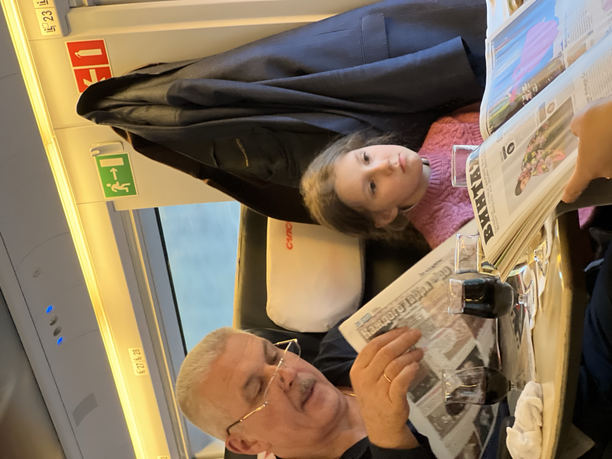 Man reads newspaper with girl on Russian train