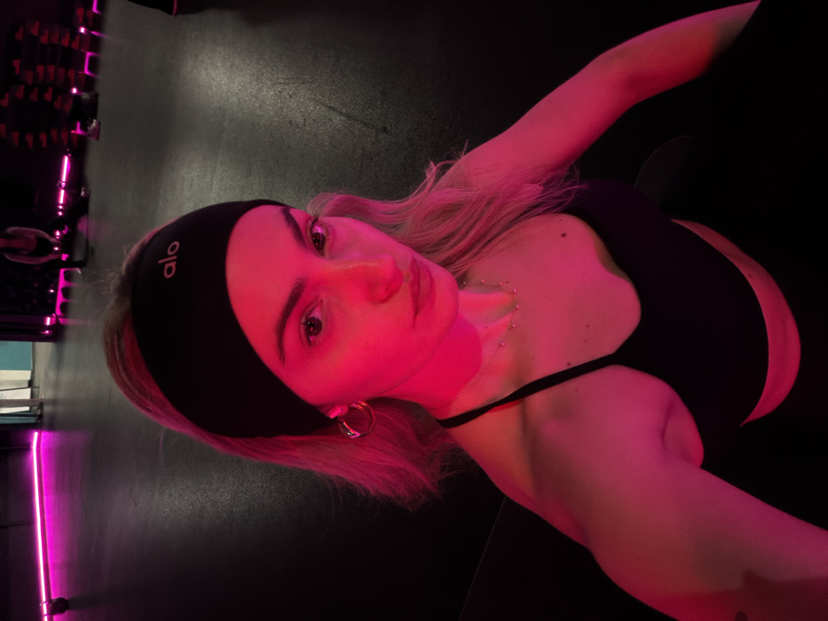 Woman takes gym selfies in neon-lit Salford fitness center