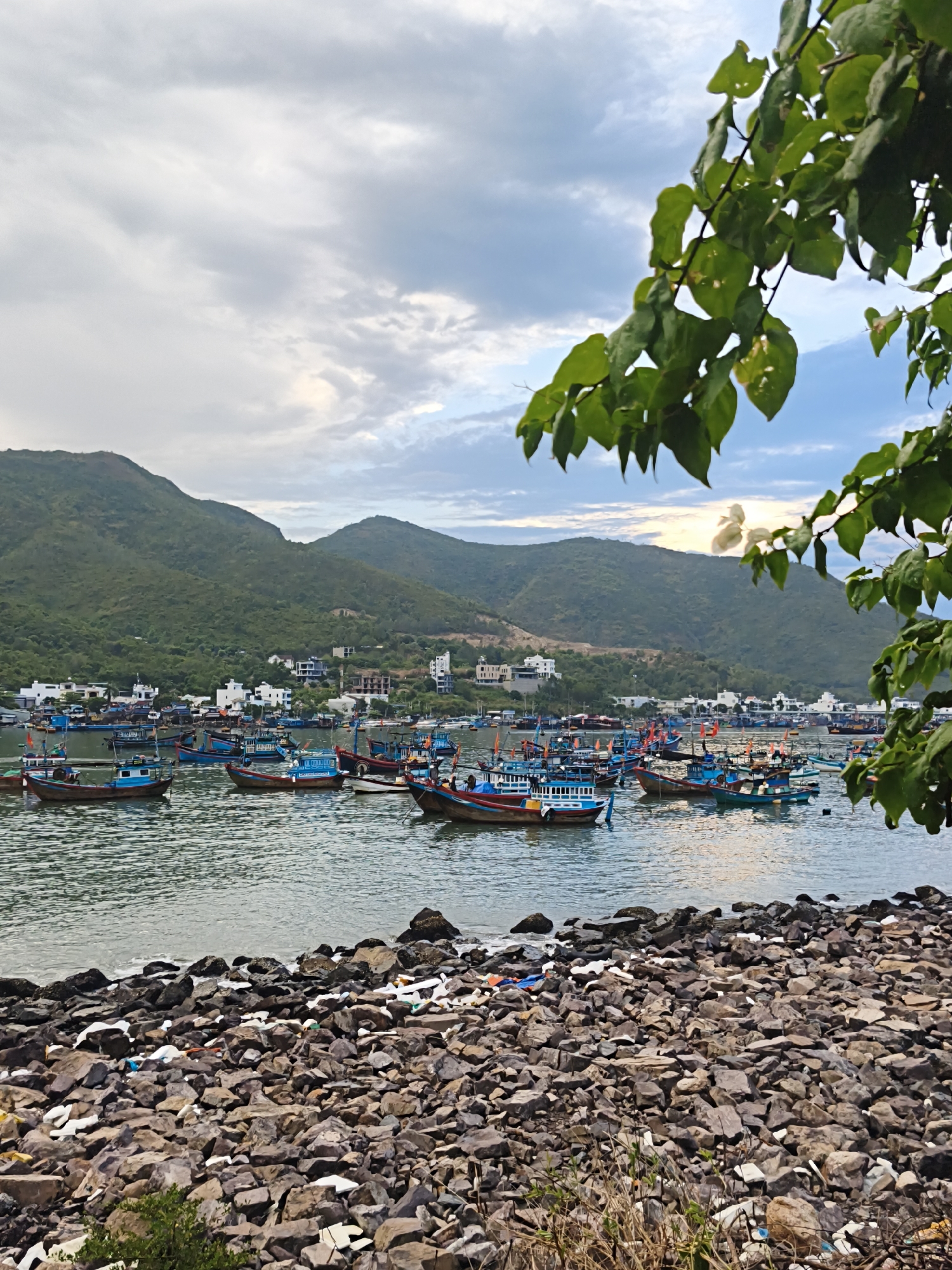 Nha Trang harbor: fishing boats, mountain backdrop, and coastal debris