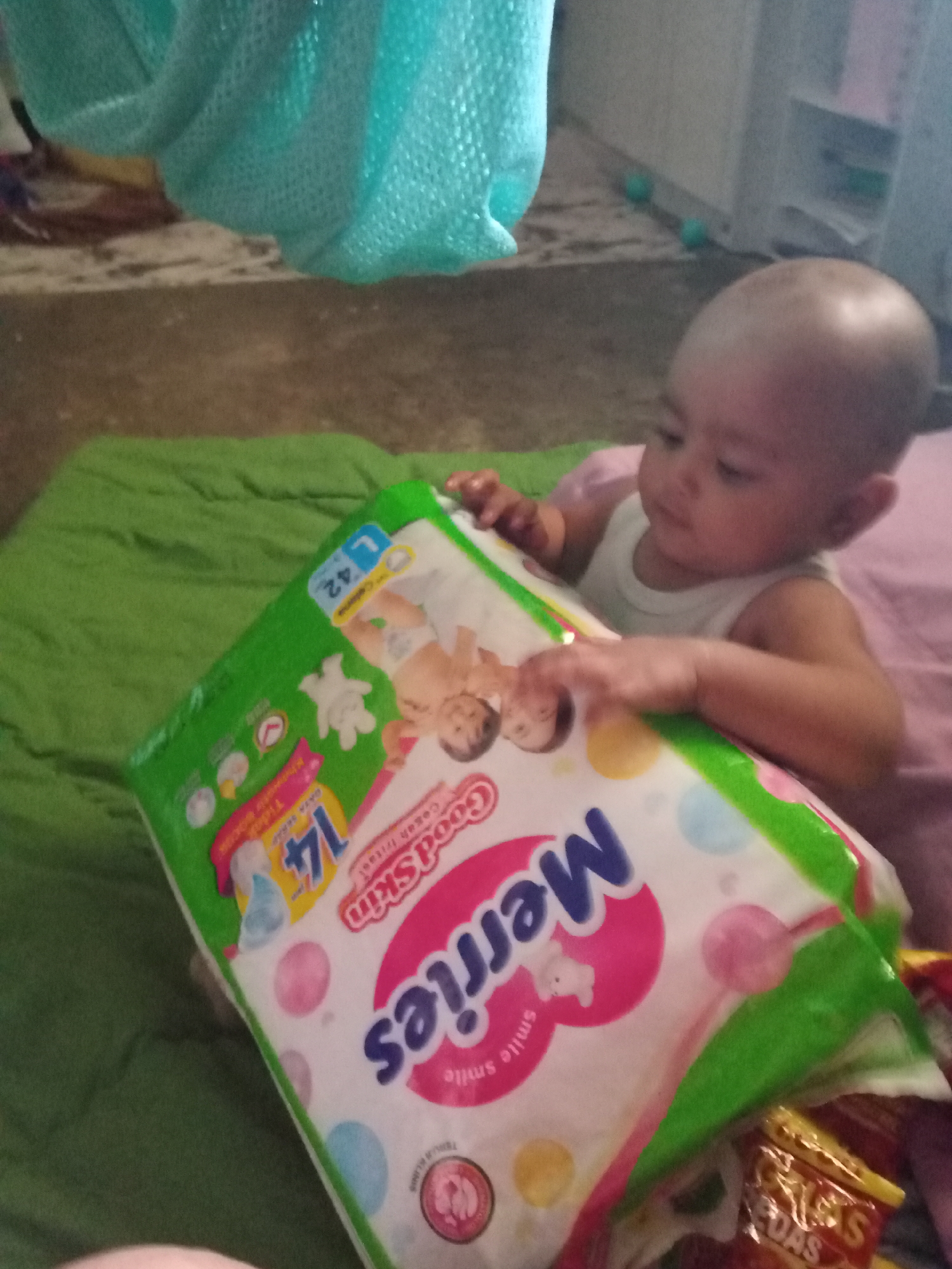 Baby surrounded by snack packets and diapers on blanket