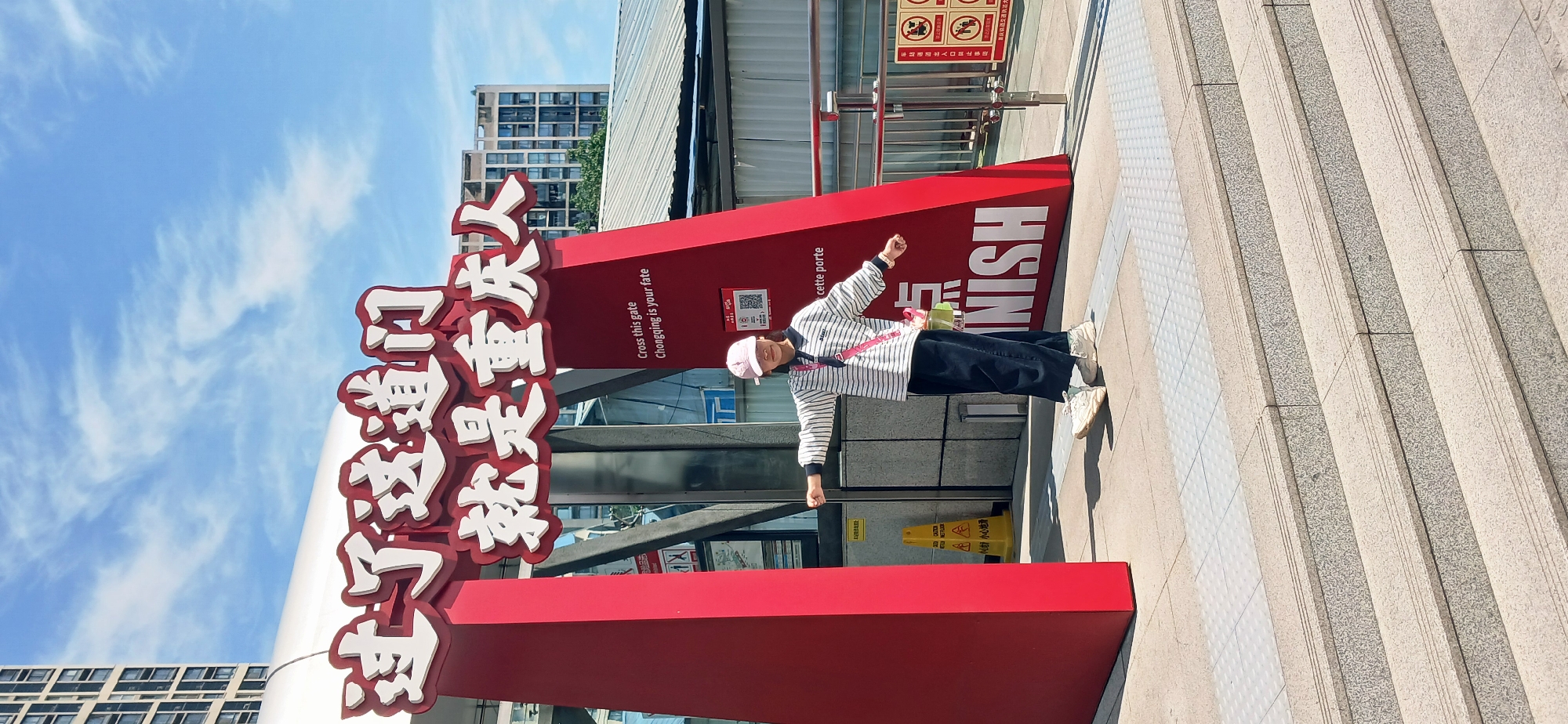 Woman poses by bilingual gate sign in Chongqing