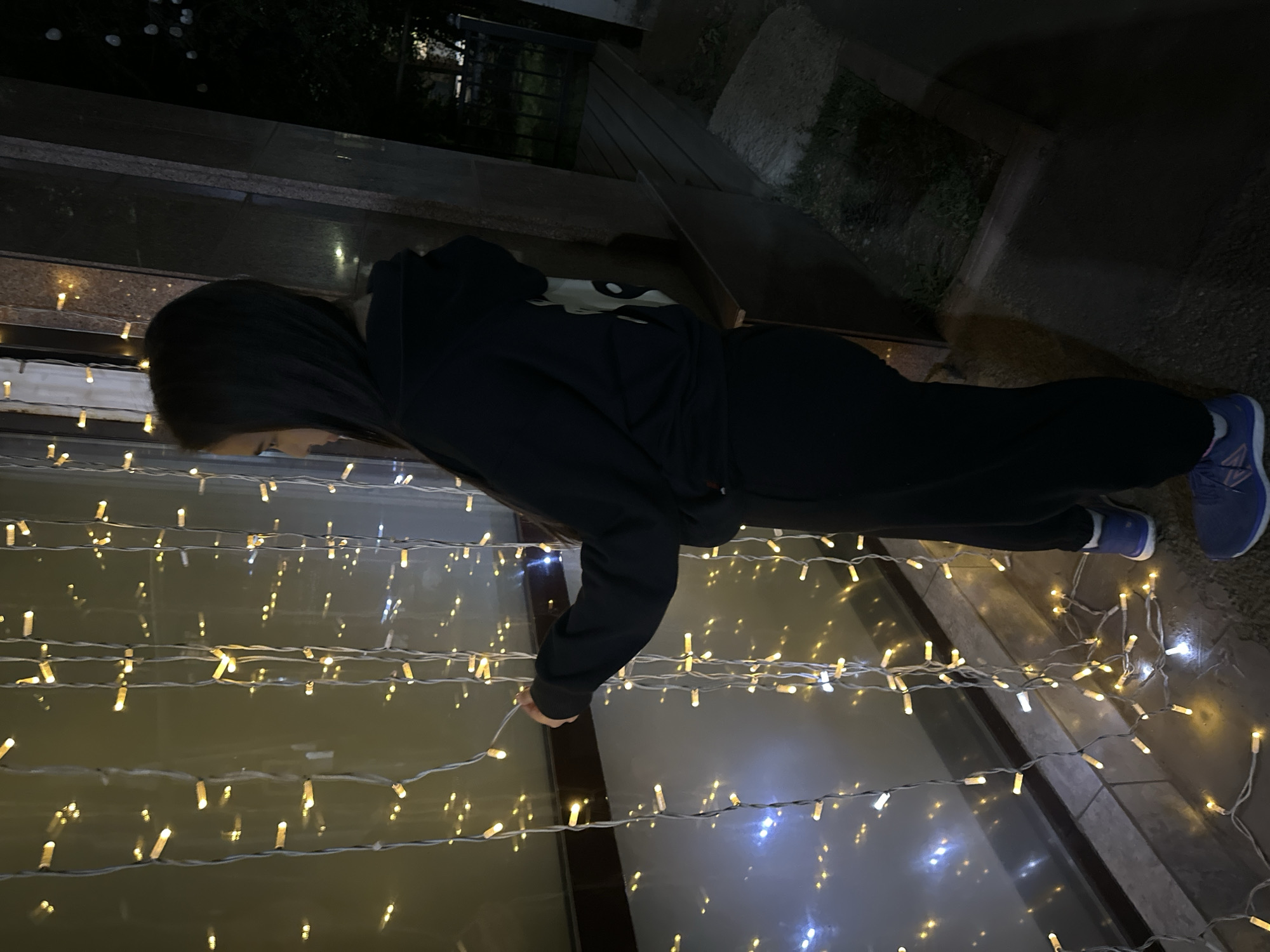 Outside a fairy-lit Almaty entrance in a graphic black hoodie