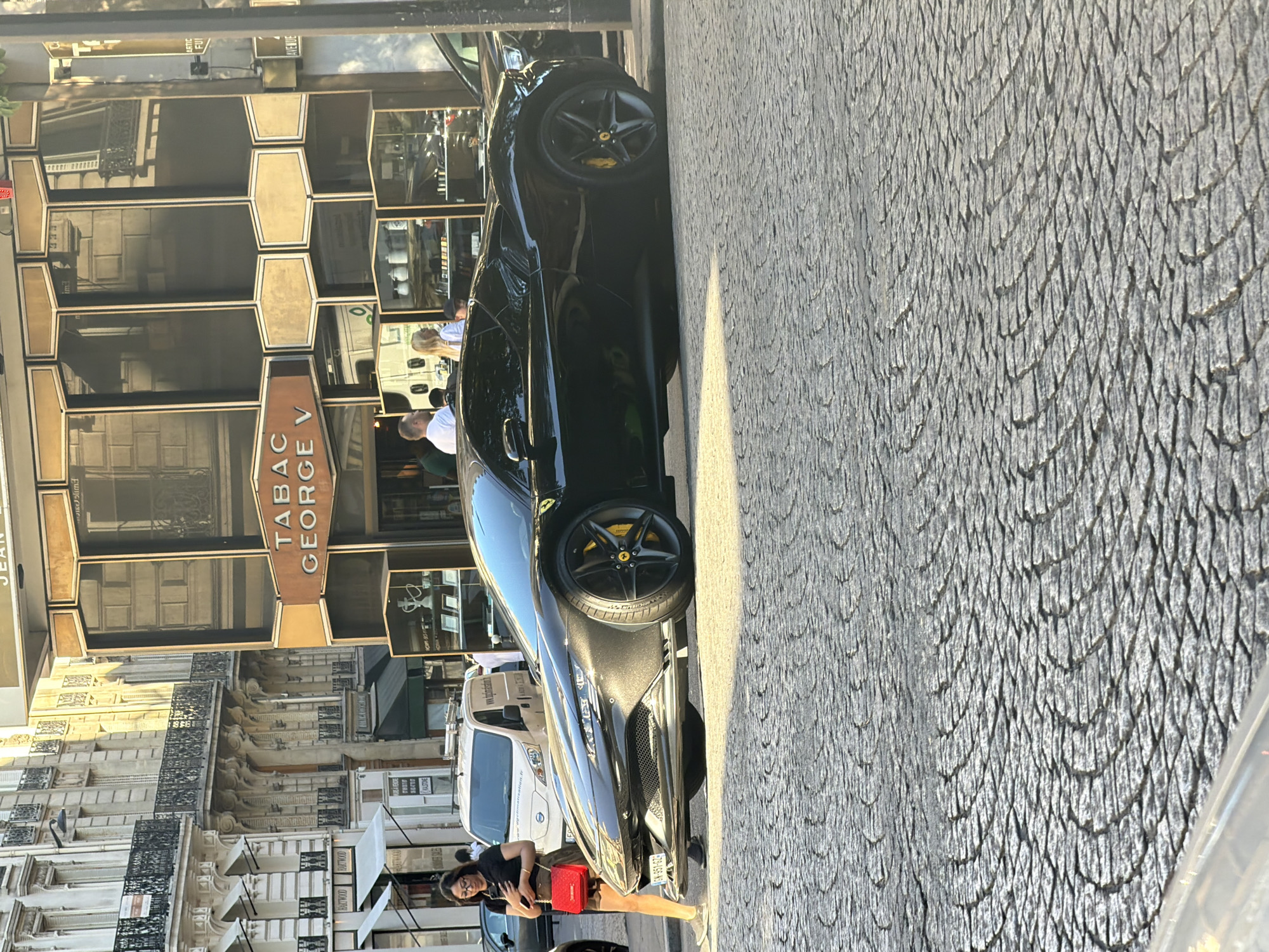 Black Ferrari parked on cobblestone street in historic Paris