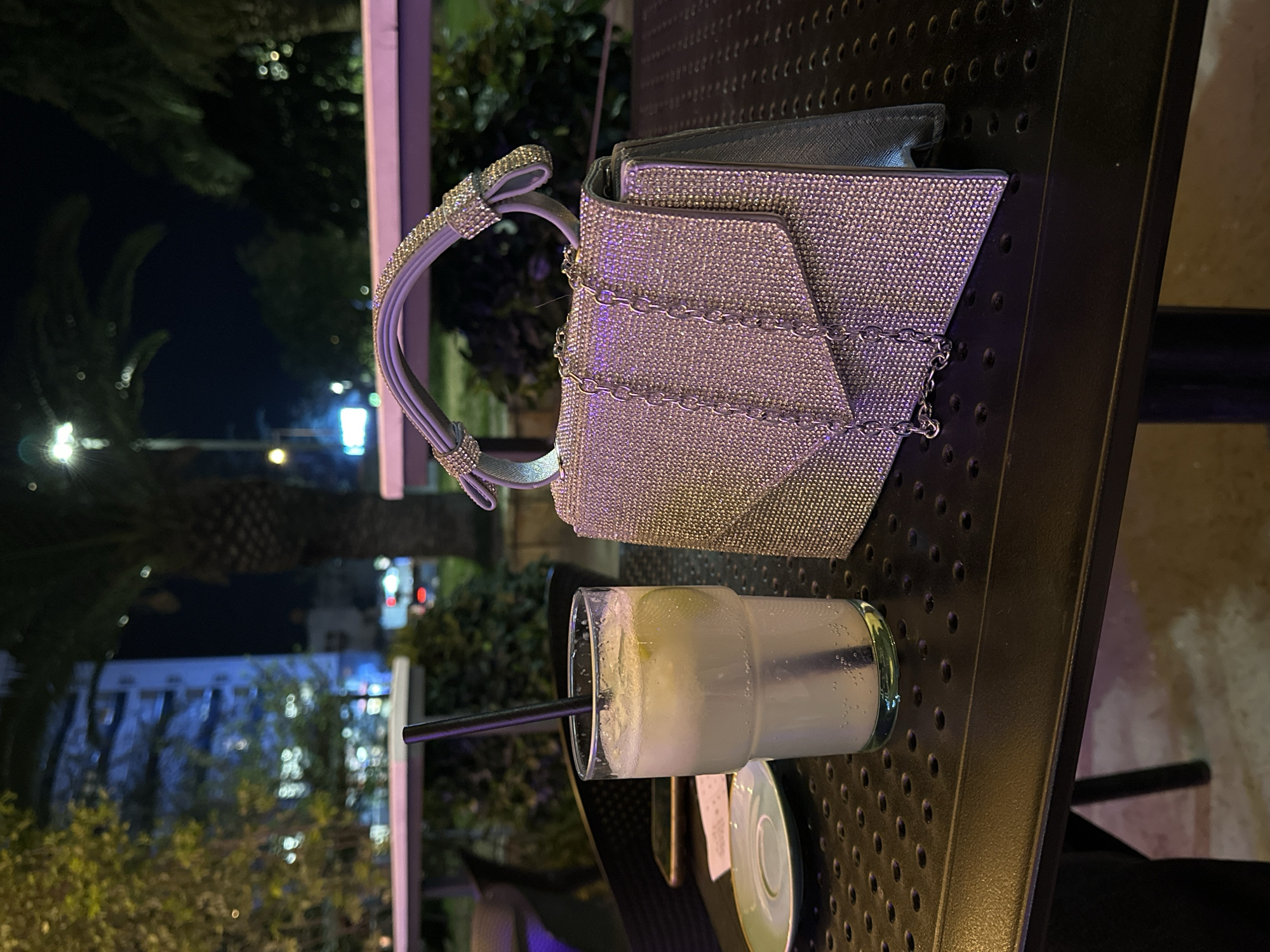 Evening cocktail and handbag captured on metal table in Polje