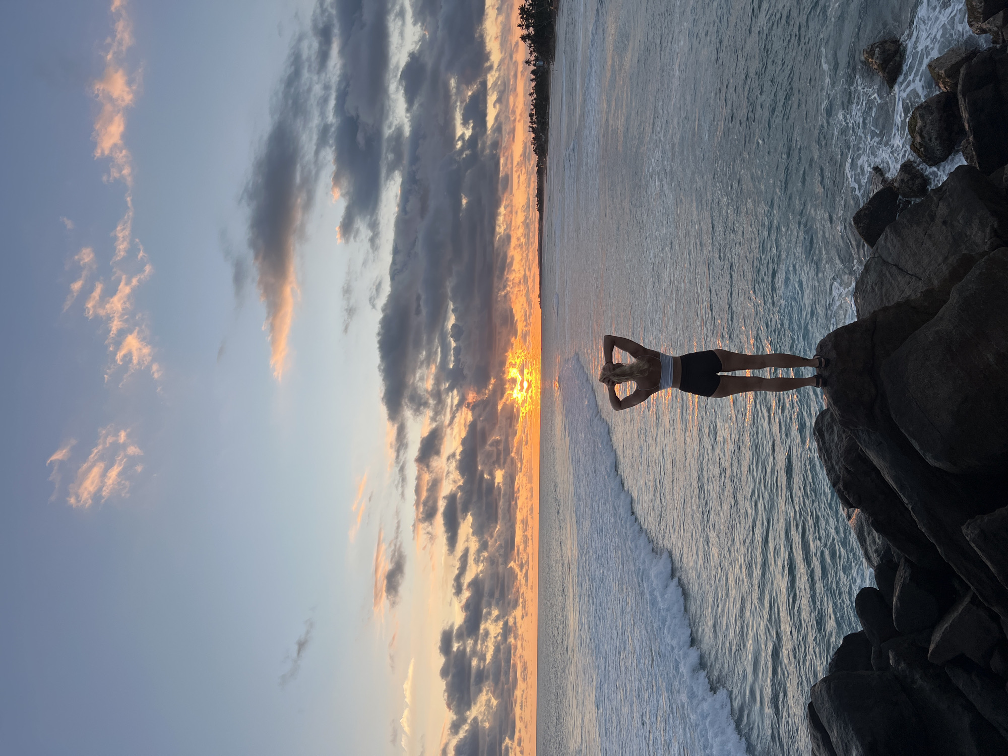 Woman poses on rocks during dramatic sunset at Goviyapana beach