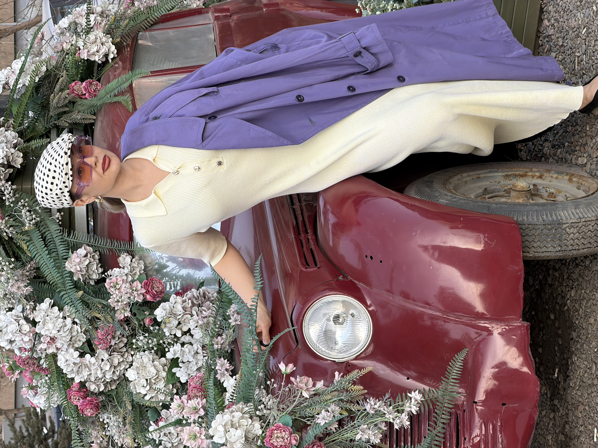 Woman poses on flower-decorated vintage truck at Russian nursery