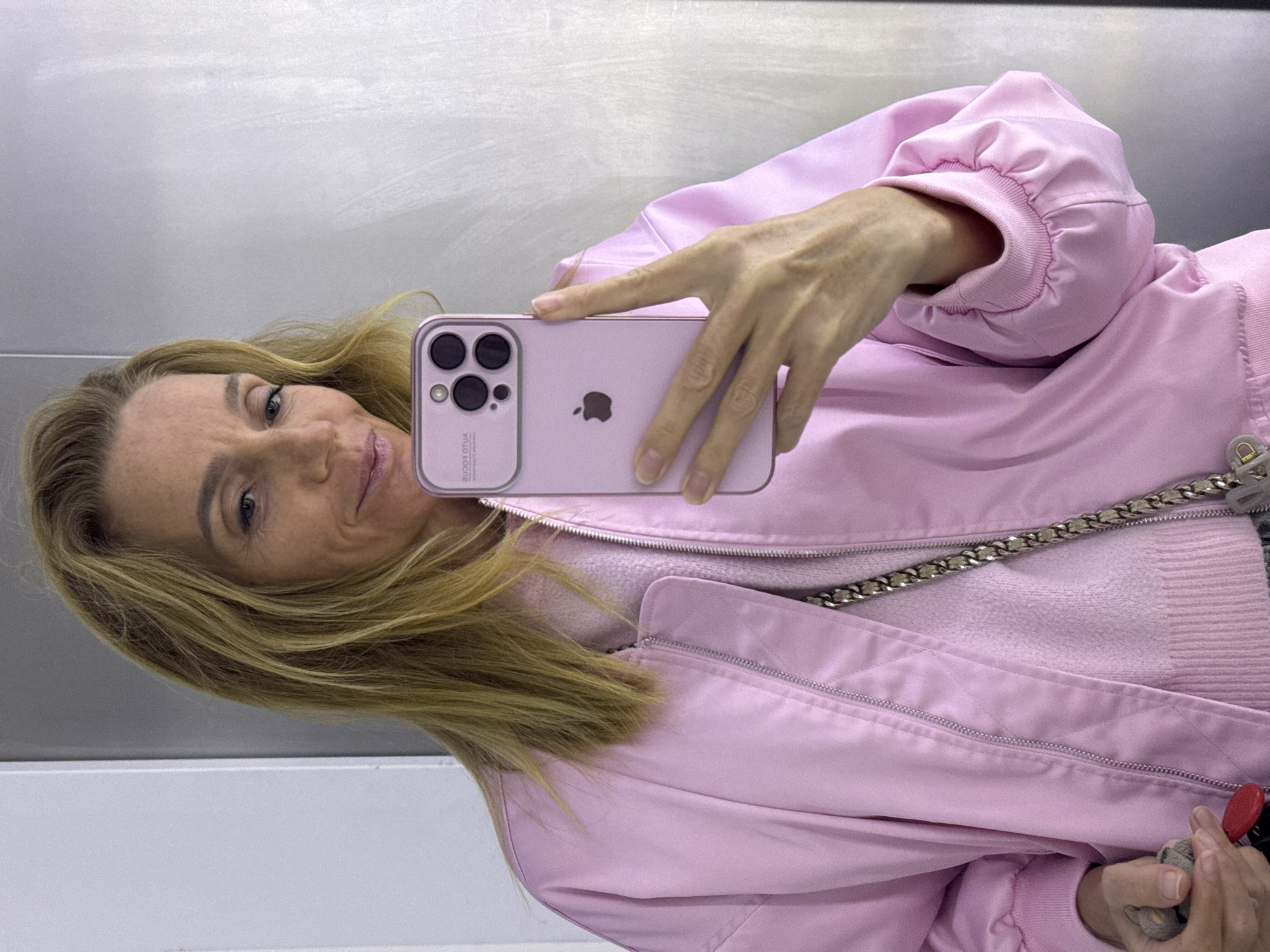 Woman takes pink iPhone selfie against metallic wall in Russia