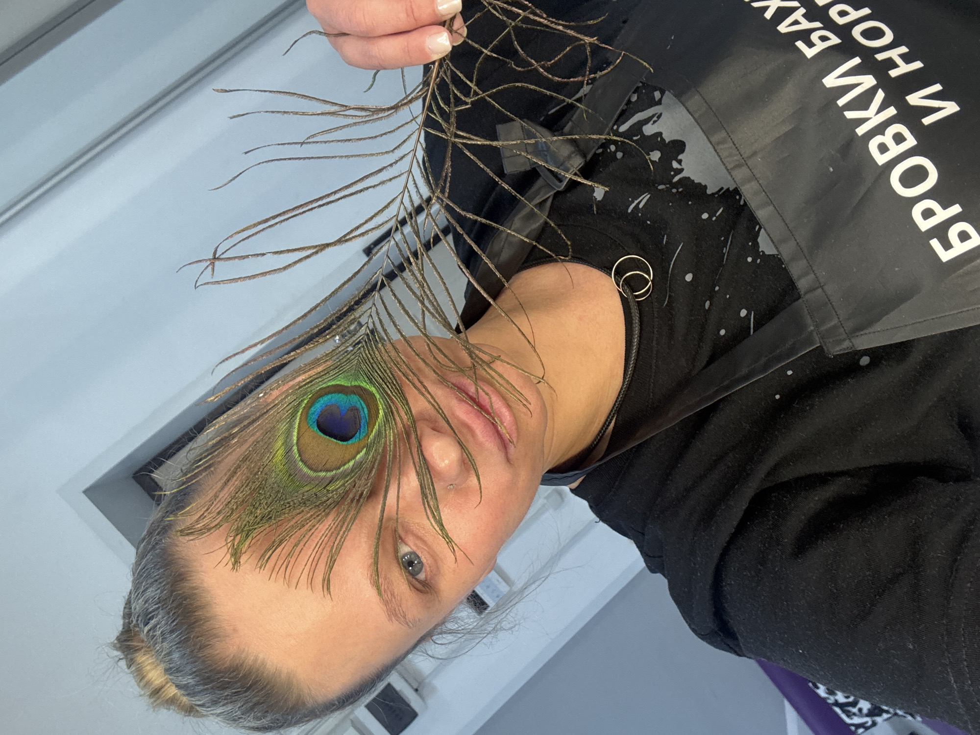 Person holds peacock feather over eye in Perm, Russia