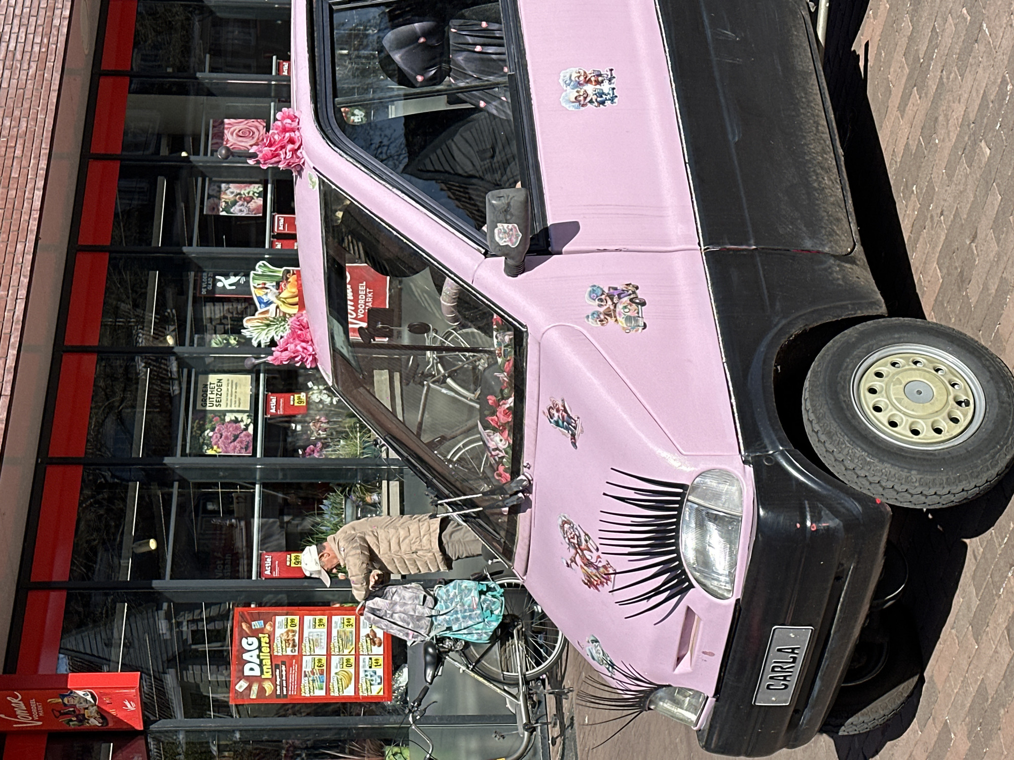 Contrasting vehicles spotted in Amsterdam: decorated microcar, Mazda wheel