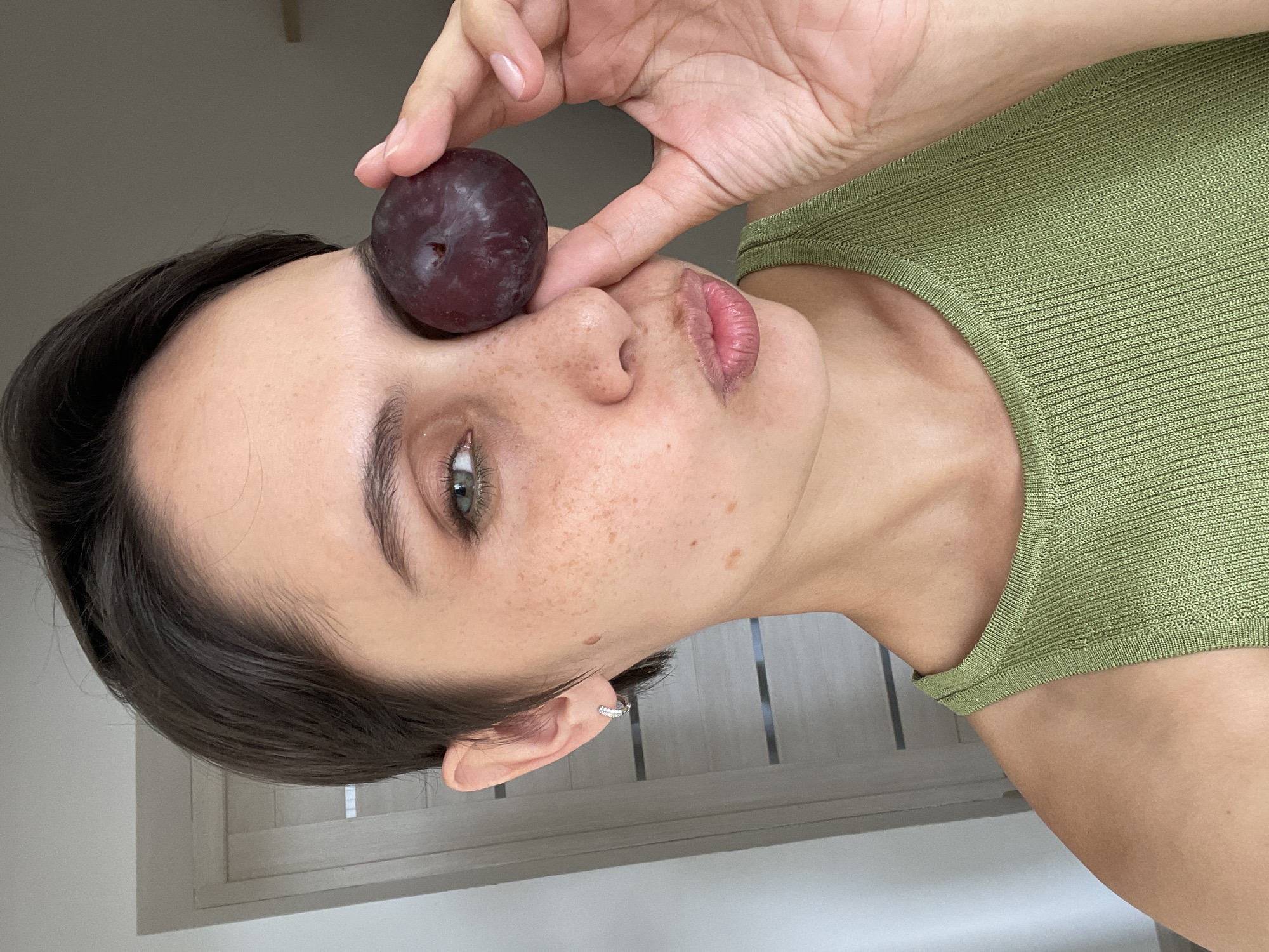 Woman photographed with plum against face in Izhevsk