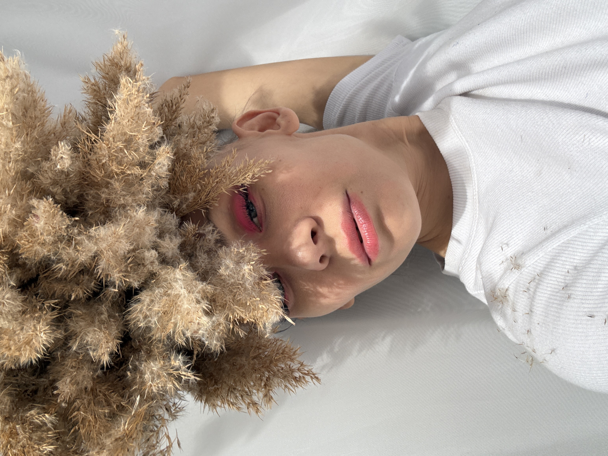 Woman with pink makeup poses indoors with pampas grass