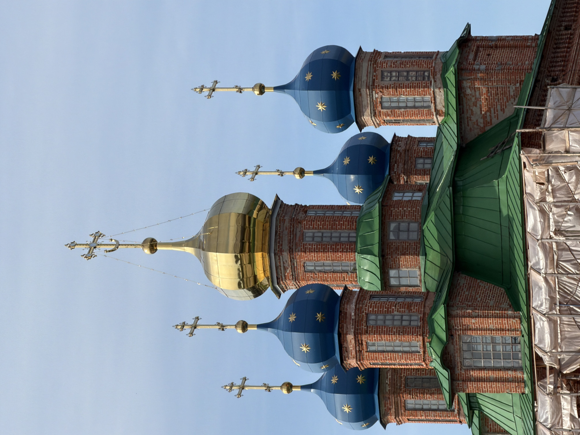 Orthodox church with blue domes beside a calm riverside