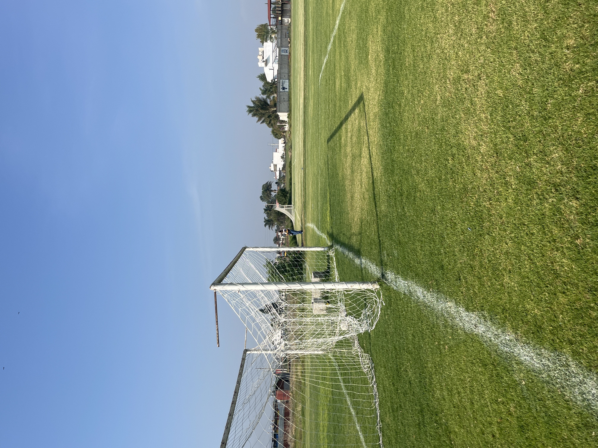 Soccer field observed under clear skies with buildings nearby