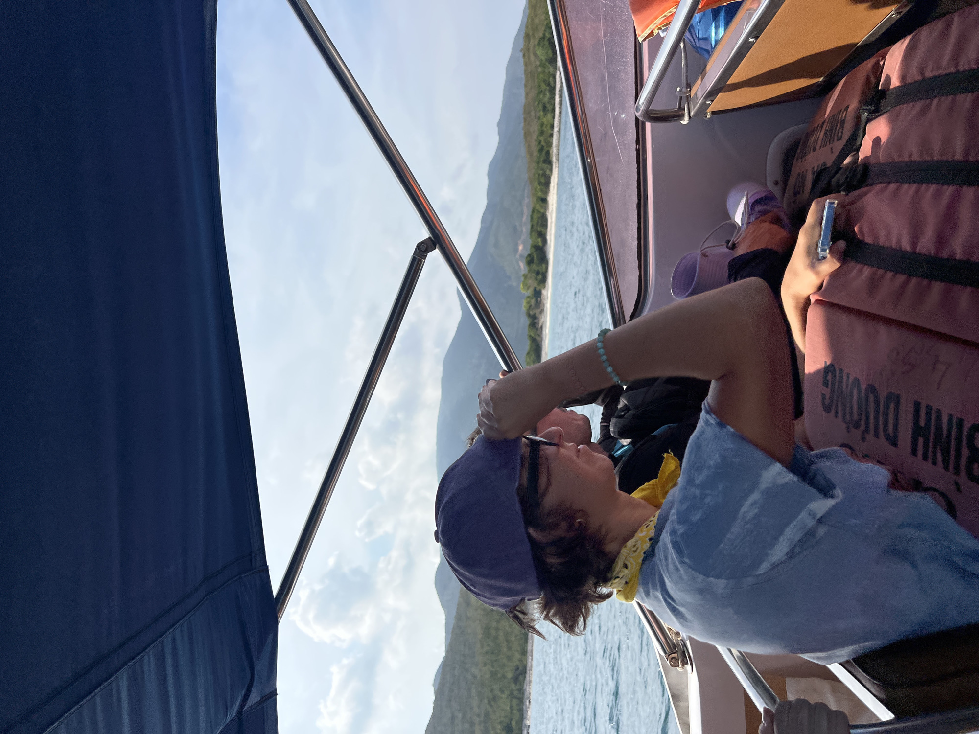 Boat passenger uses phone near orange items in Vietnam