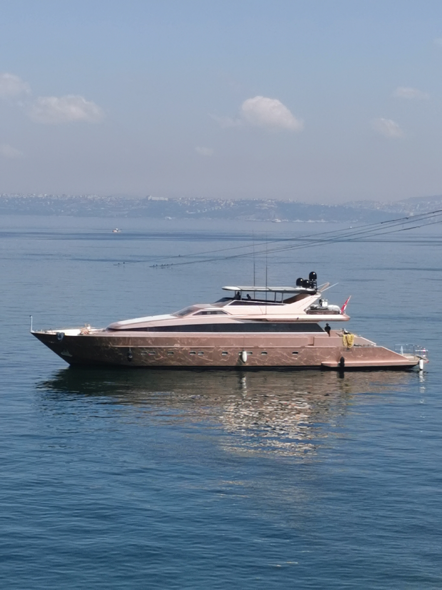 Rose-gold superyacht on calm open water, clear skies