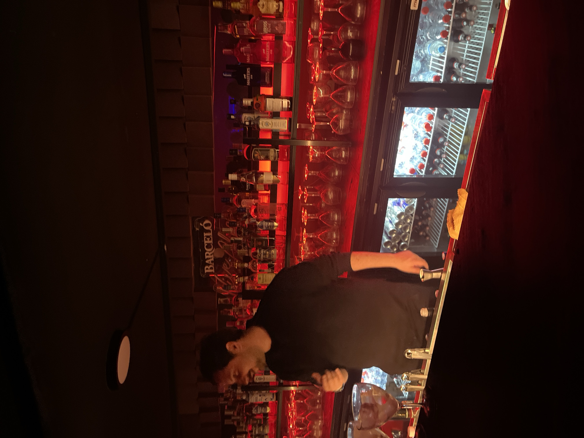 Bartender works late shift at Valencia bar with red lighting